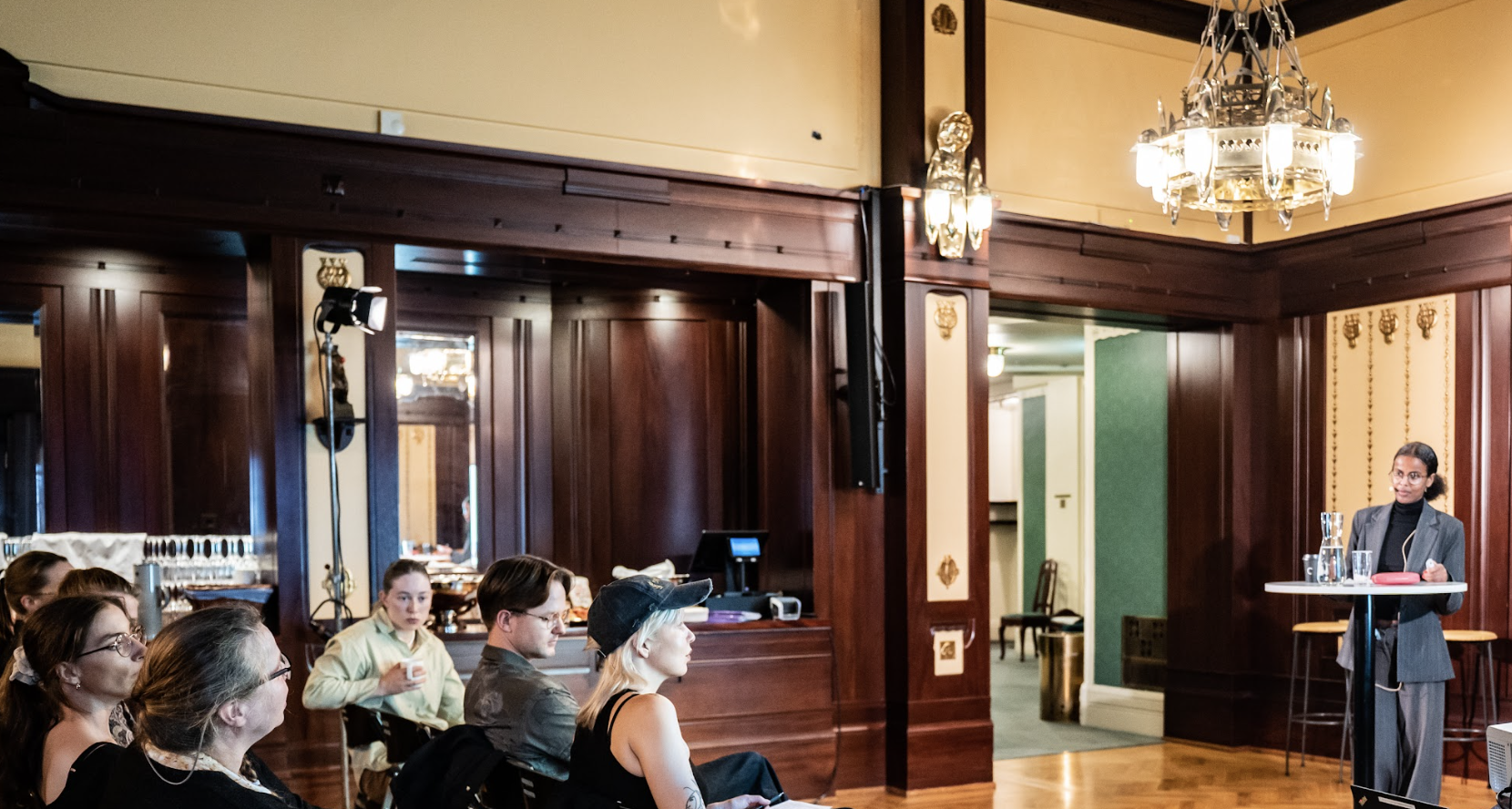 Zubeida står og holder kurs foran et sittende publikum.