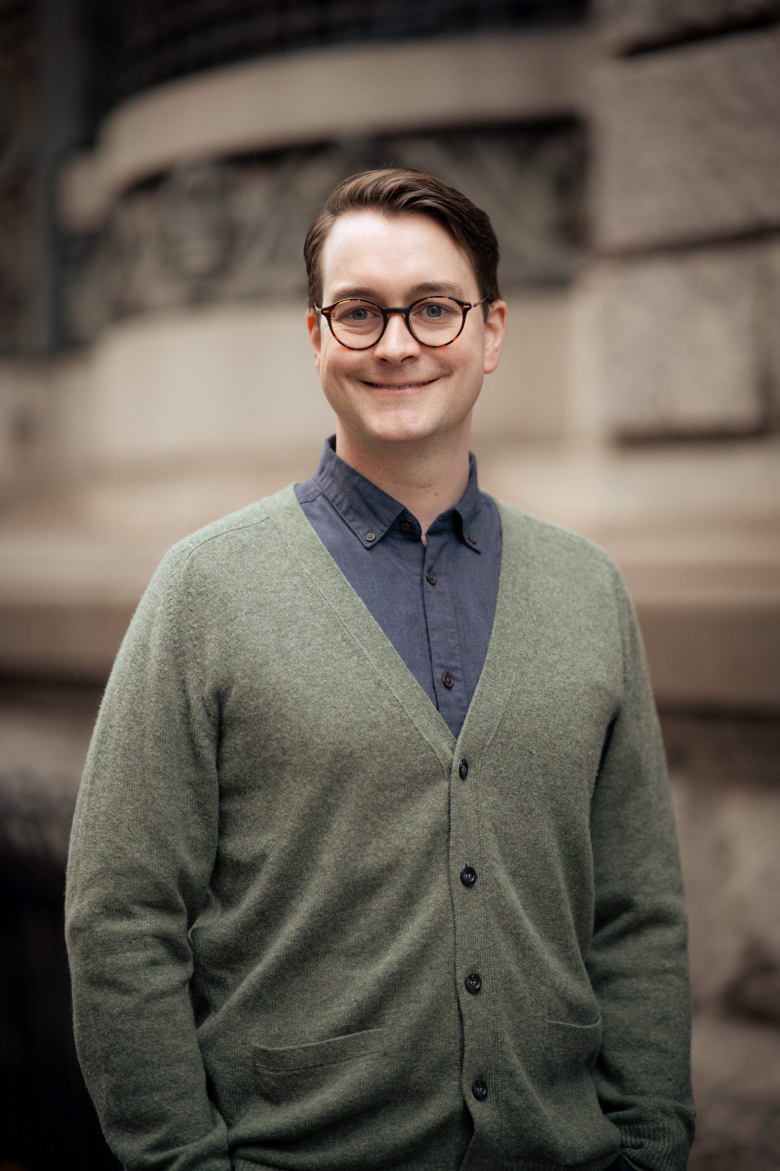 Portrett av Jacob Kreyberg som står og smiler mot brun bakgrunn.