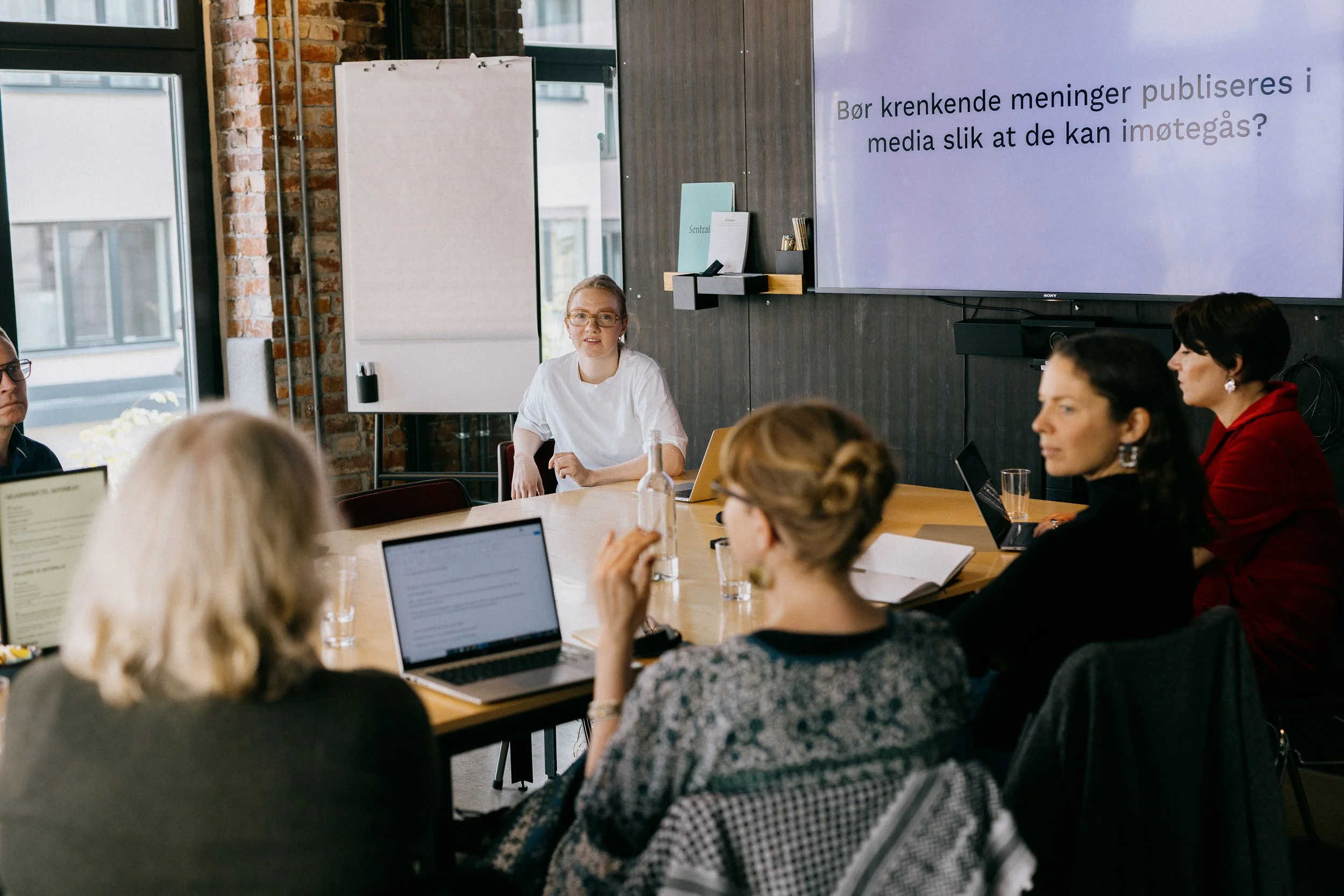 Victoria Øverby Steinland and a group of course participants discussing in a meeting room.