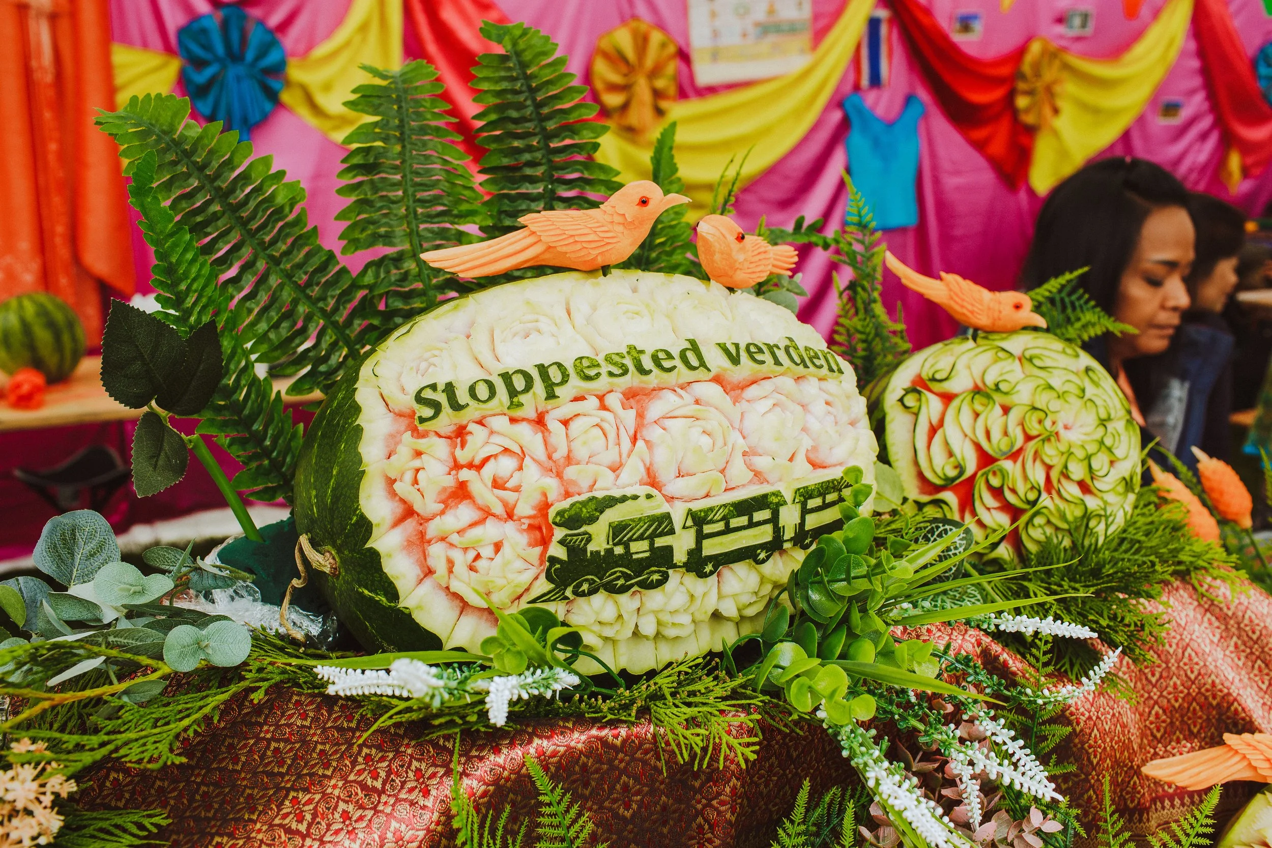 Bildet viser teksten Stoppested Verden skåret ut på en vannmelon. Med glimt av festival i bakgrunen.