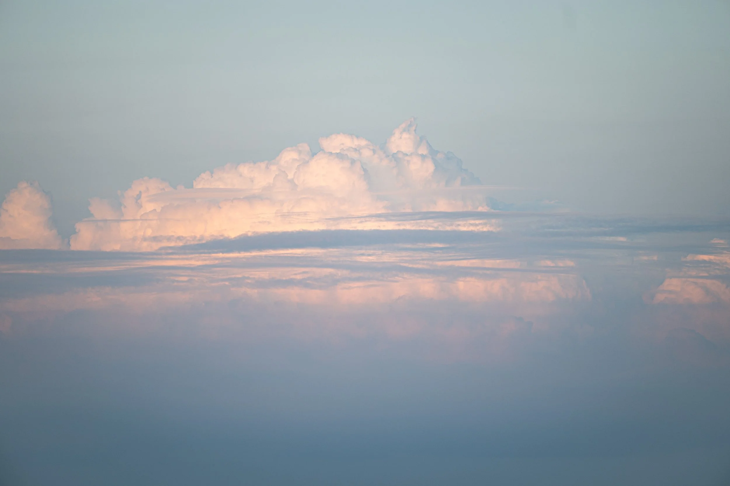 Luchtfoto van een heldere hemel met zachte, dikwijls roze en blauwe wolkenbanken.