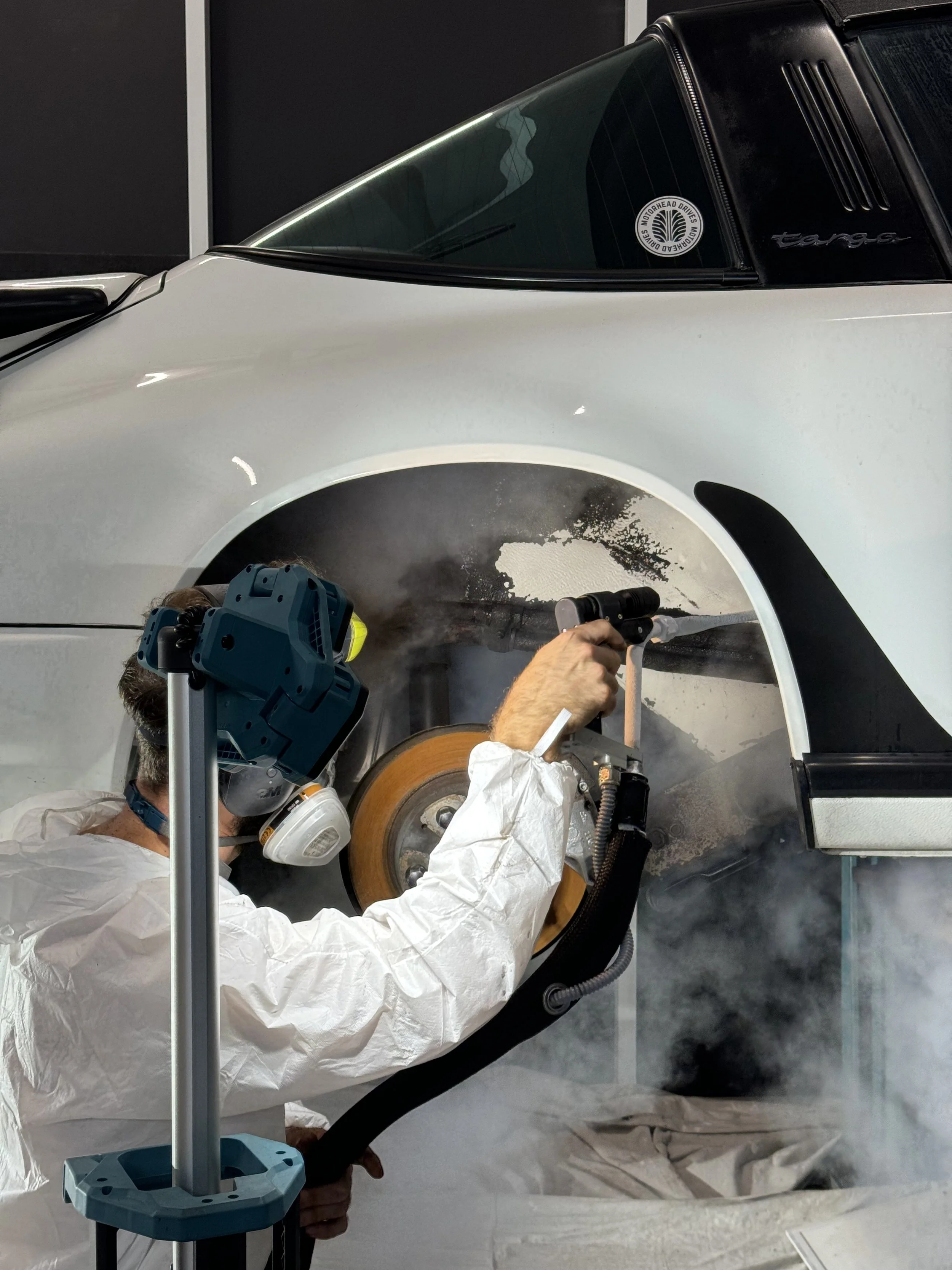 person dry ice blasting Porsche 911 g body rear wheel well removing black coating