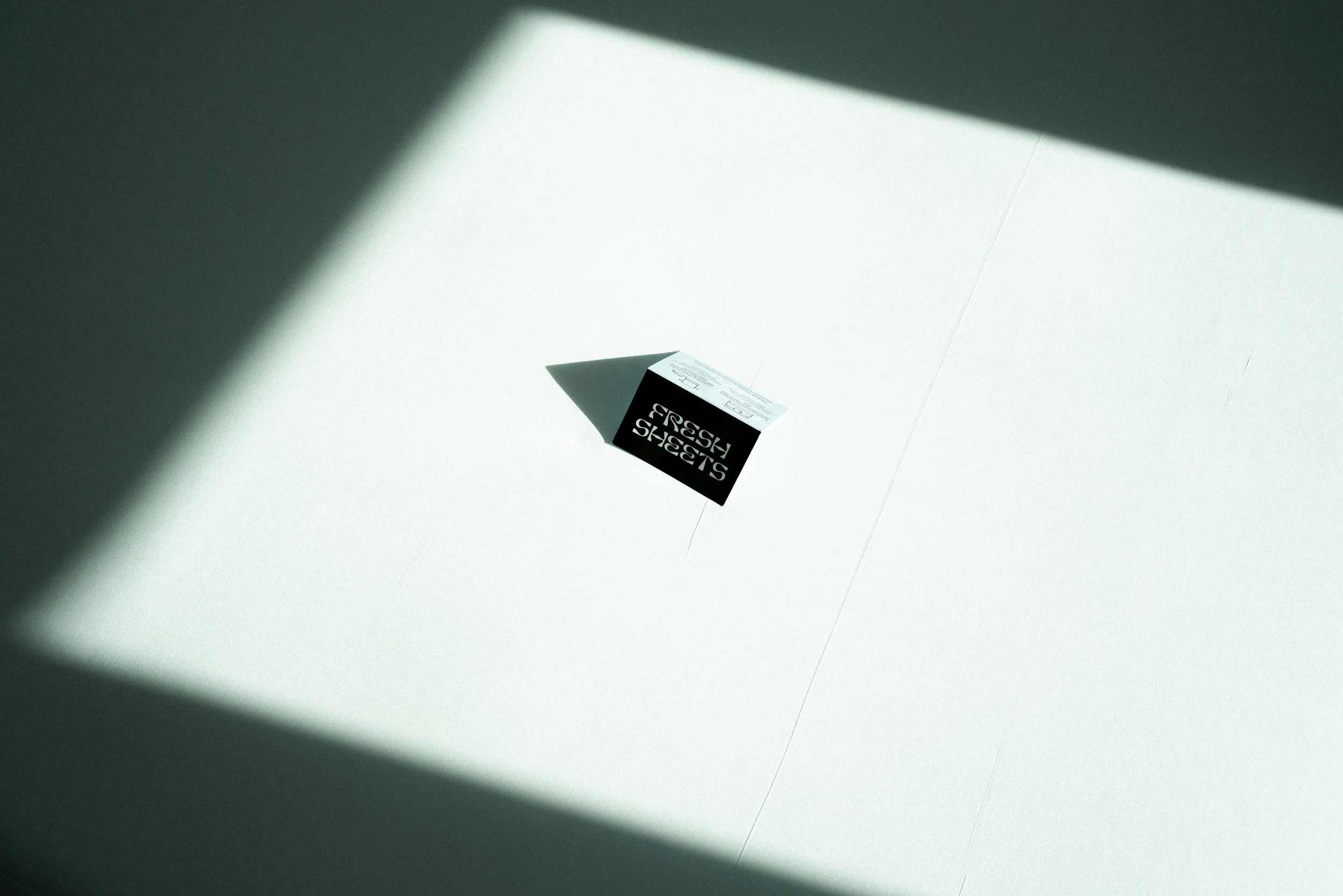 A black and white sales sign cast in shadow on a white surface.