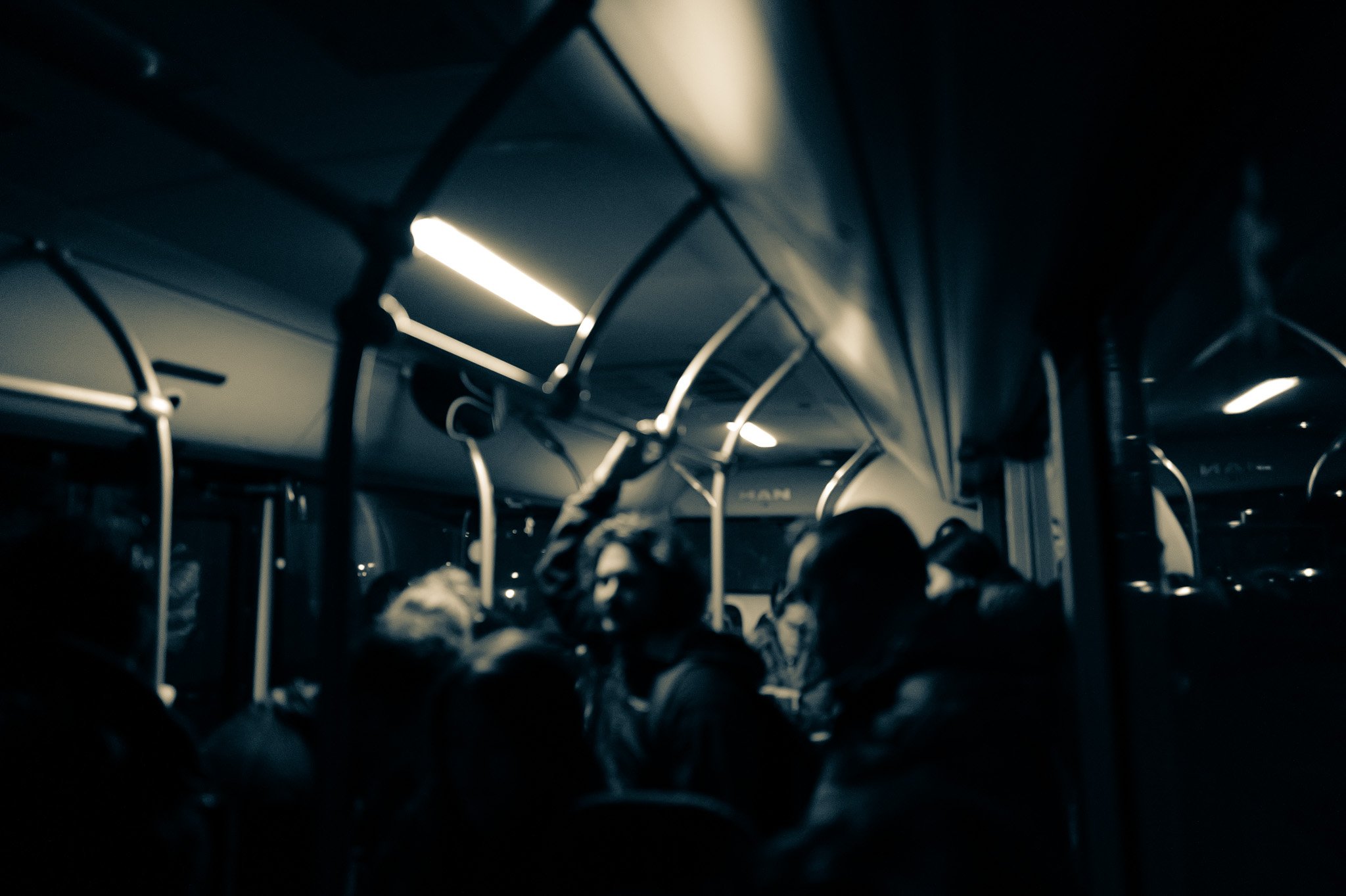 Blurry interior of a dimly lit bus with standing passengers.