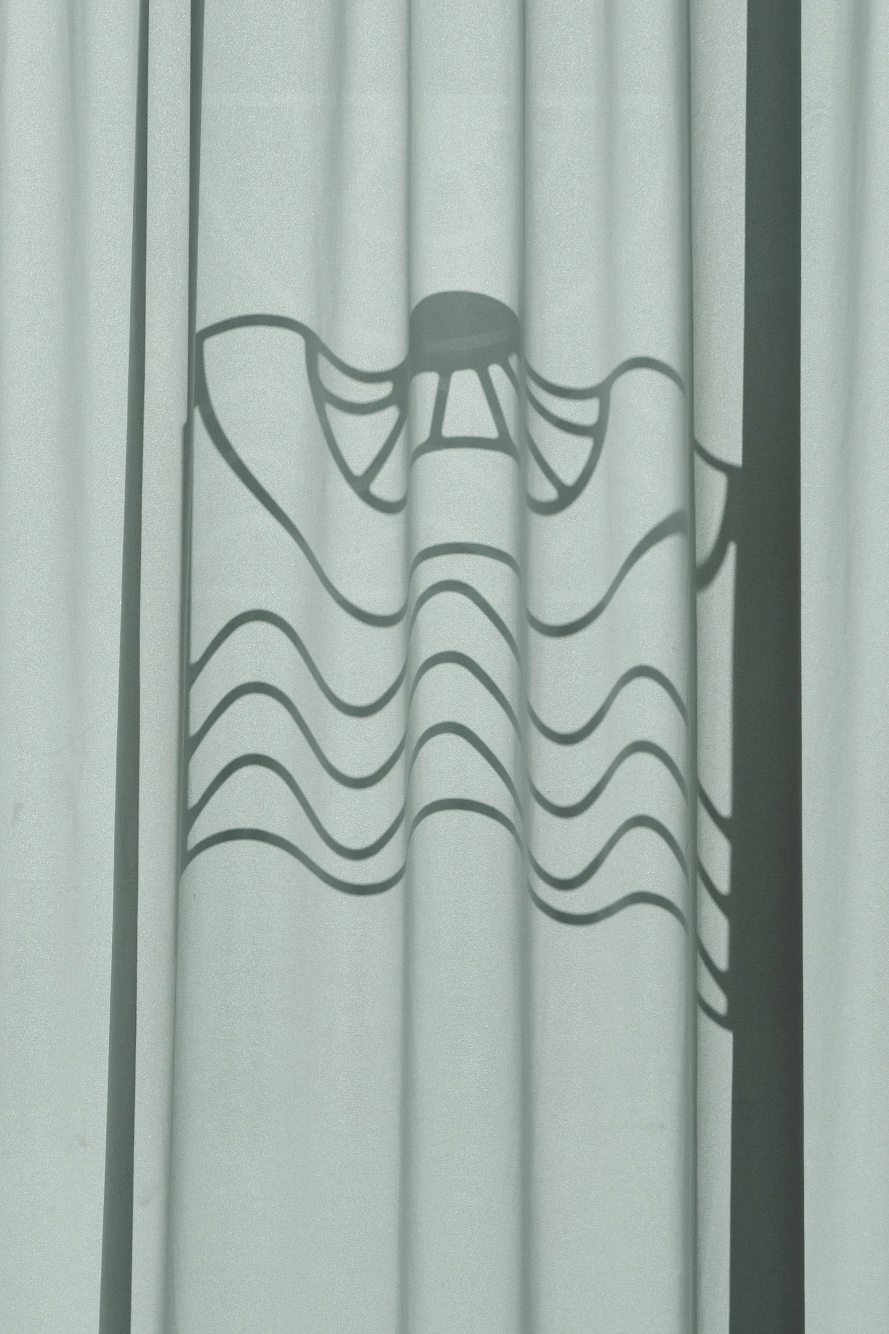 Shadow of a curtain with a design resembling a butterfly.