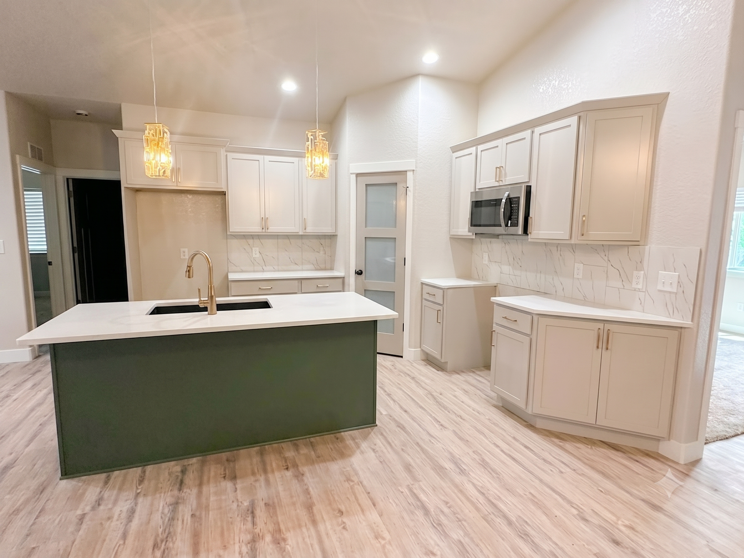 Bright Kitchen with gold hardware, light cabinets with green island, light quartz countertops