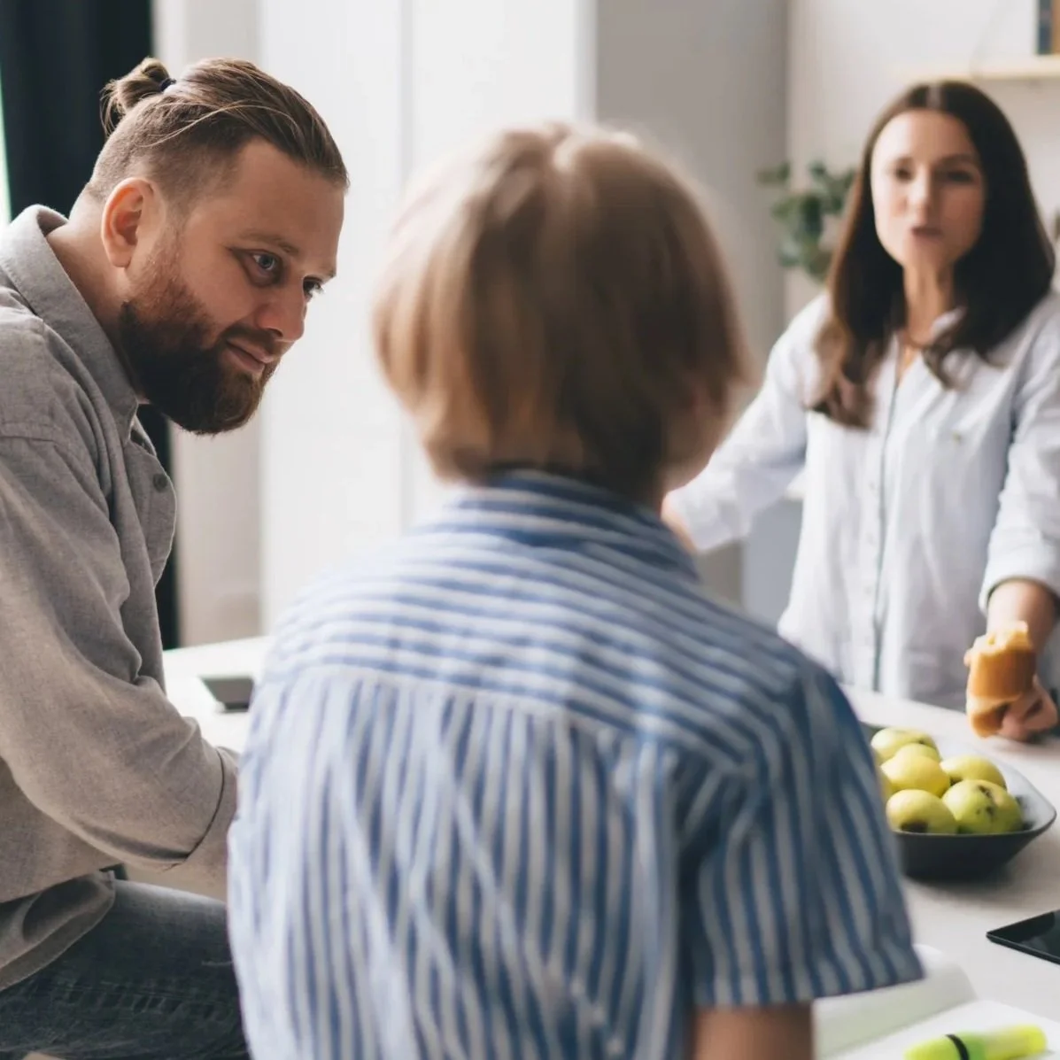 Mother and father talking to son at kitchen table.