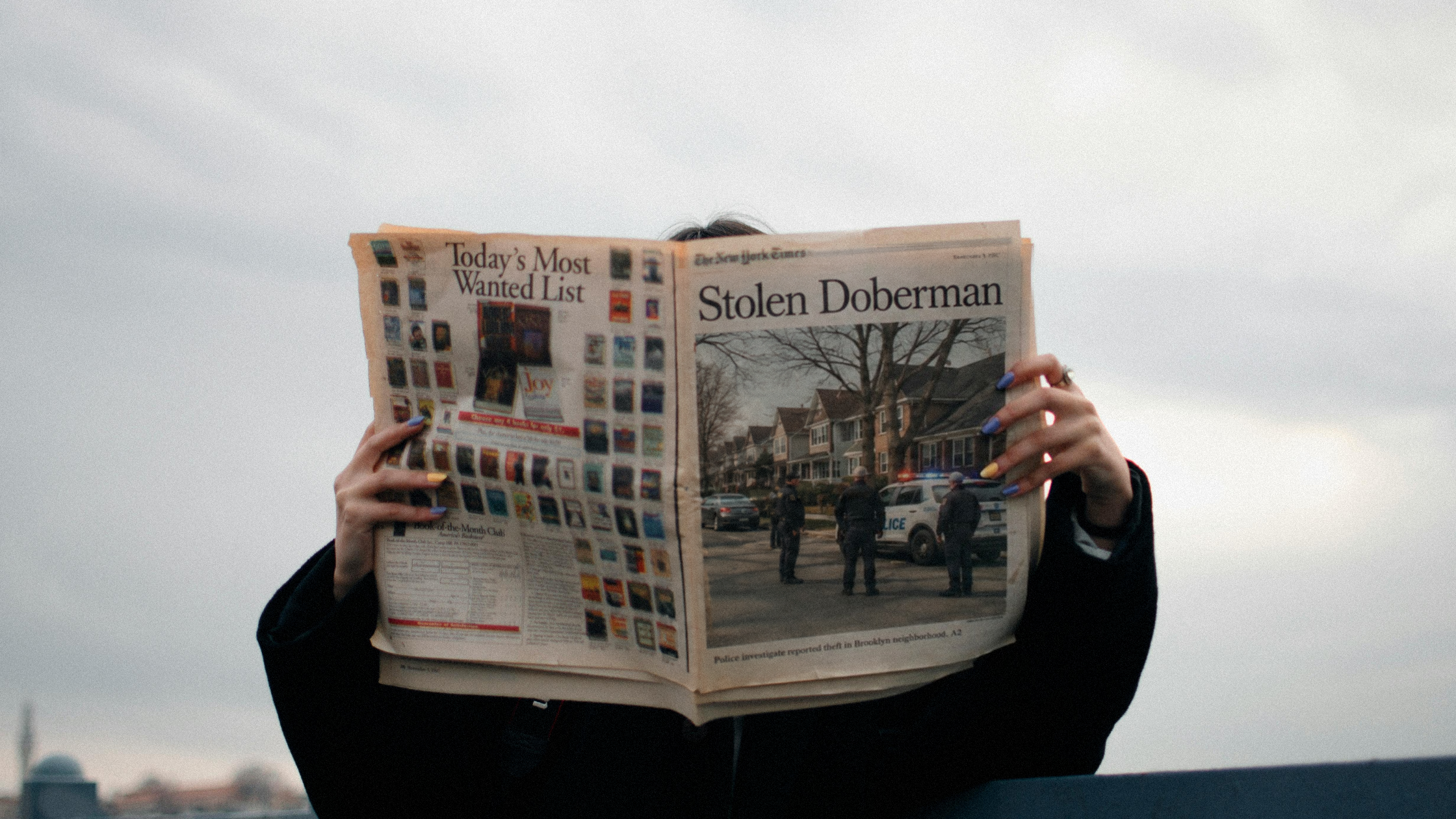 Woman holding a newspaper with a headline that reads Stolen Doberman.