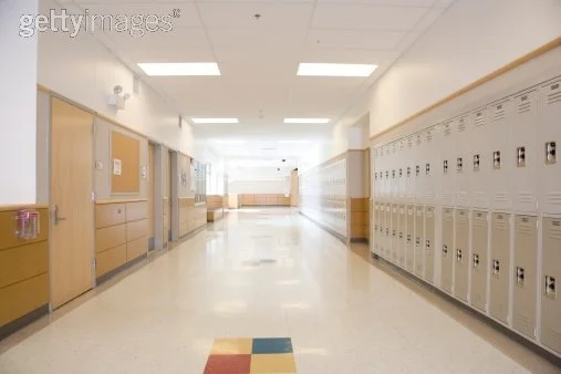 Empty school hallway with lockers and classroom doors.