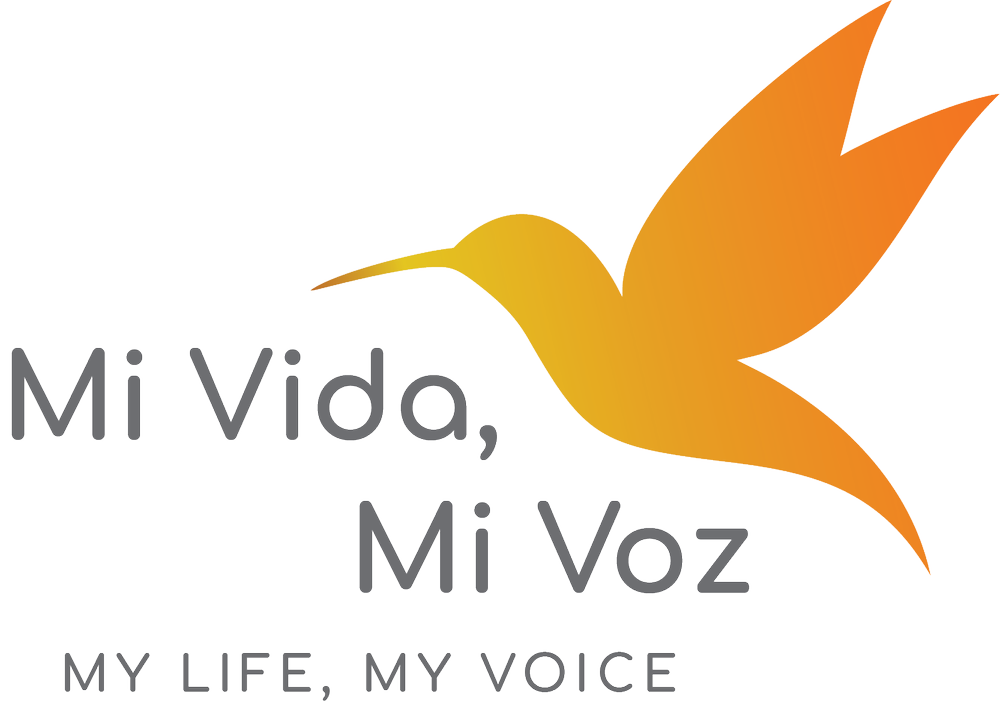 A logo featuring a stylized orange hummingbird with outstretched wings above Spanish text 'Mi Vida, Mi Voz' and English text 'My Life, My Voice'.