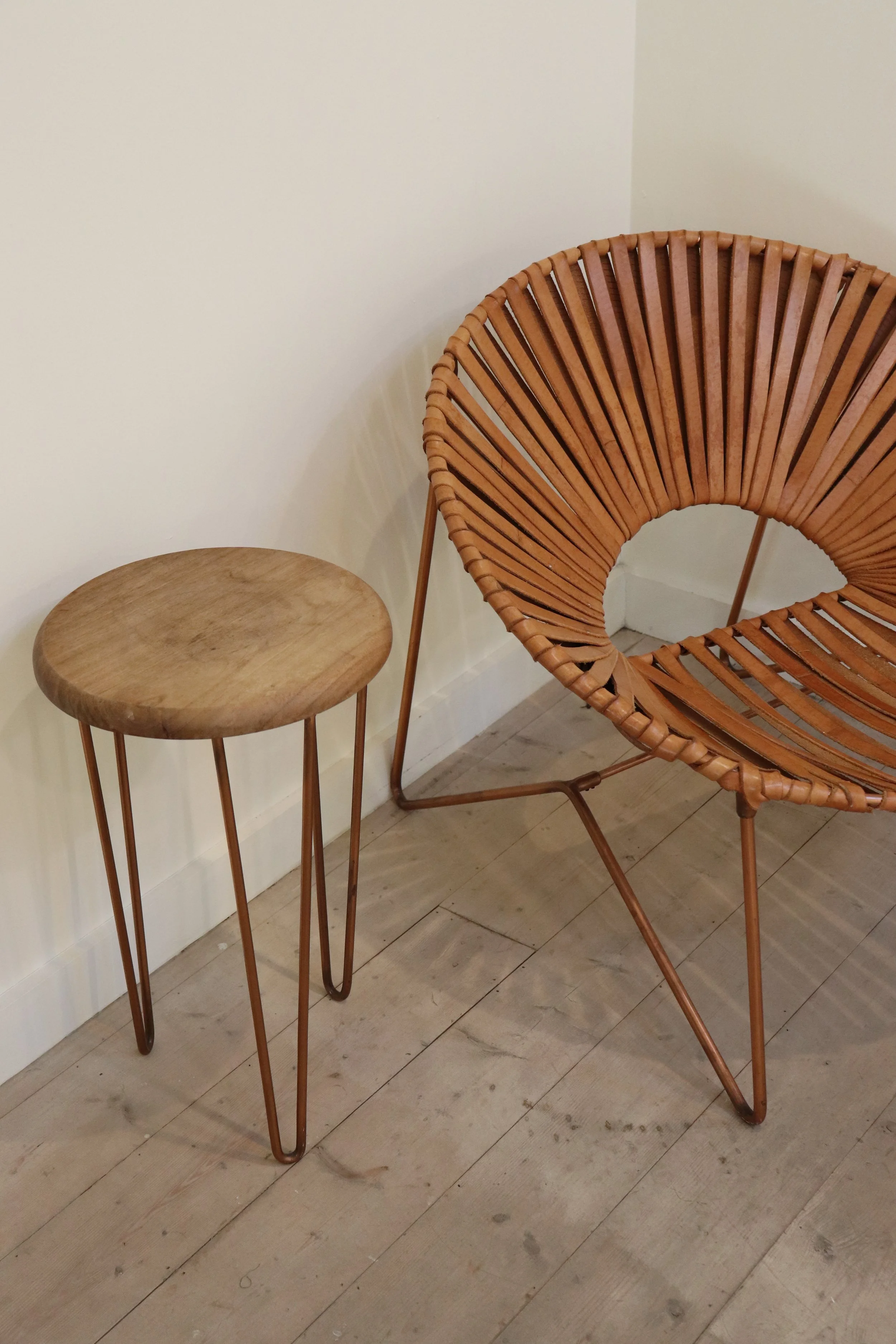 A wooden side table with metal hairpin legs and a modern round rattan lounge chair with a curved design.
