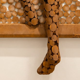 Gros plan d’une sculpture murale en bois composée de rondelles de branches formant une forme abstraite.