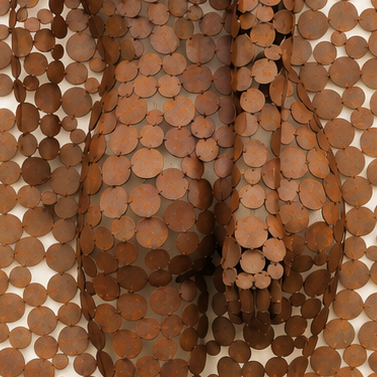 Gros plan d’une sculpture abstraite recouverte de rondelles de bois superposées.