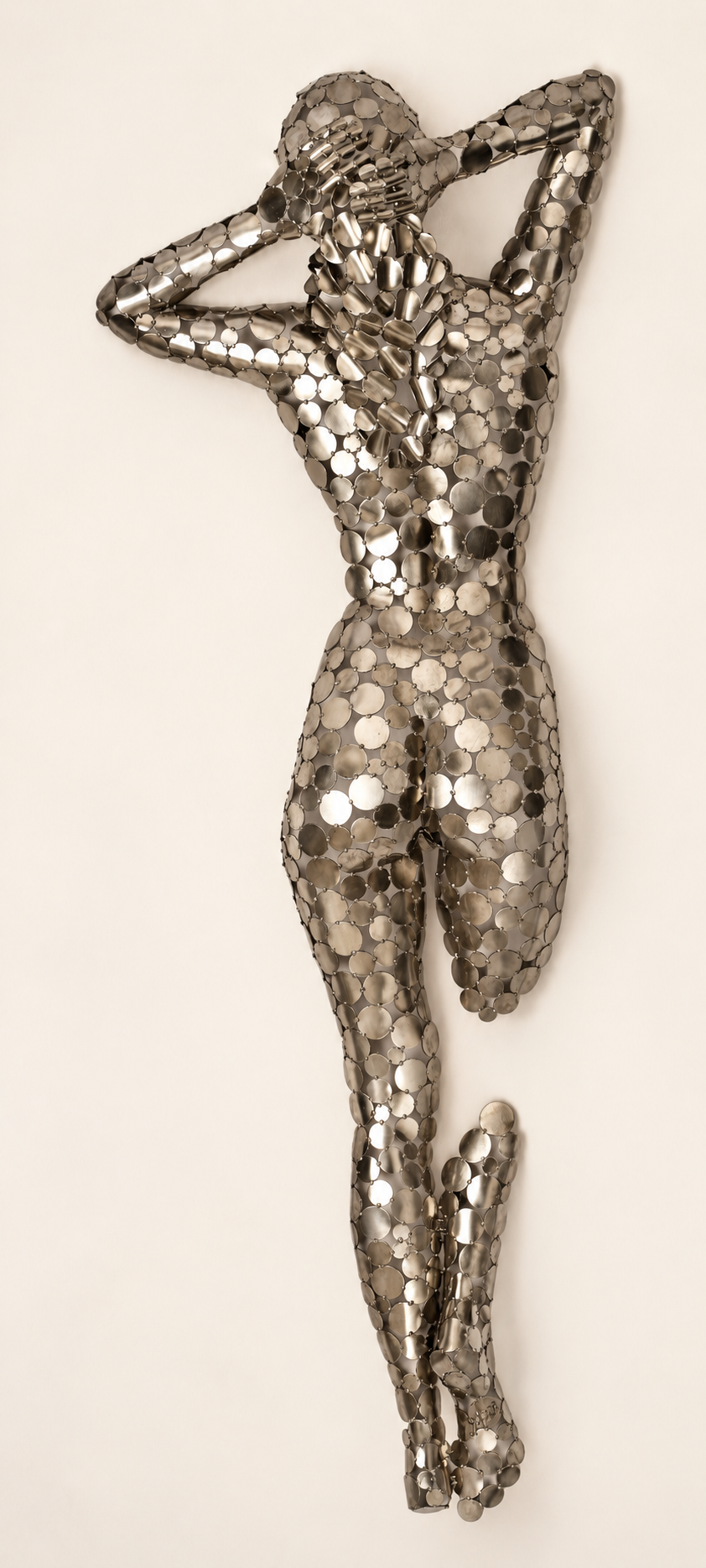 Sculpture murale métallique représentant une danseuse en mouvement, composée de petits disques argentés.