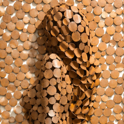 Gros plan d’une sculpture abstraite composée de rondelles de bois circulaires aux teintes brunes et dorées.