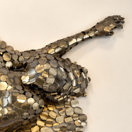 Gros plan d’une sculpture abstraite en métal recouverte de petites pastilles métalliques superposées.