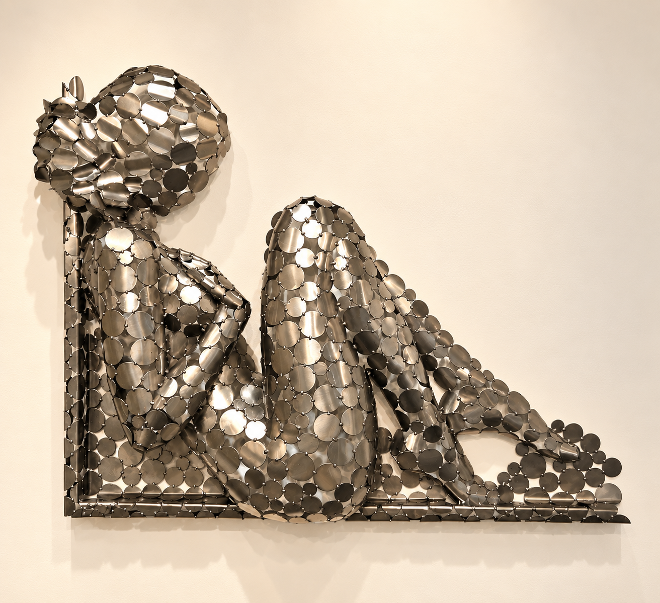 Sculpture murale métallique représentant une chaussure à talon haut, composée de disques métalliques assemblés.