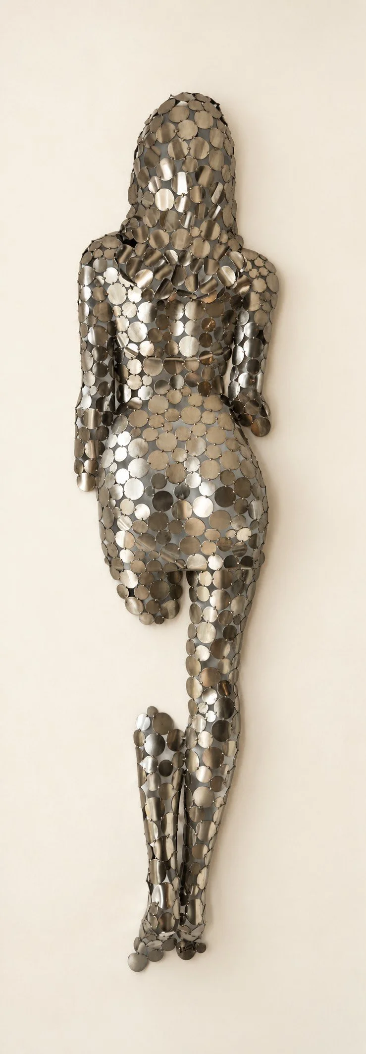 Sculpture murale métallique représentant une silhouette humaine stylisée, composée de nombreuses pastilles métalliques argentées.