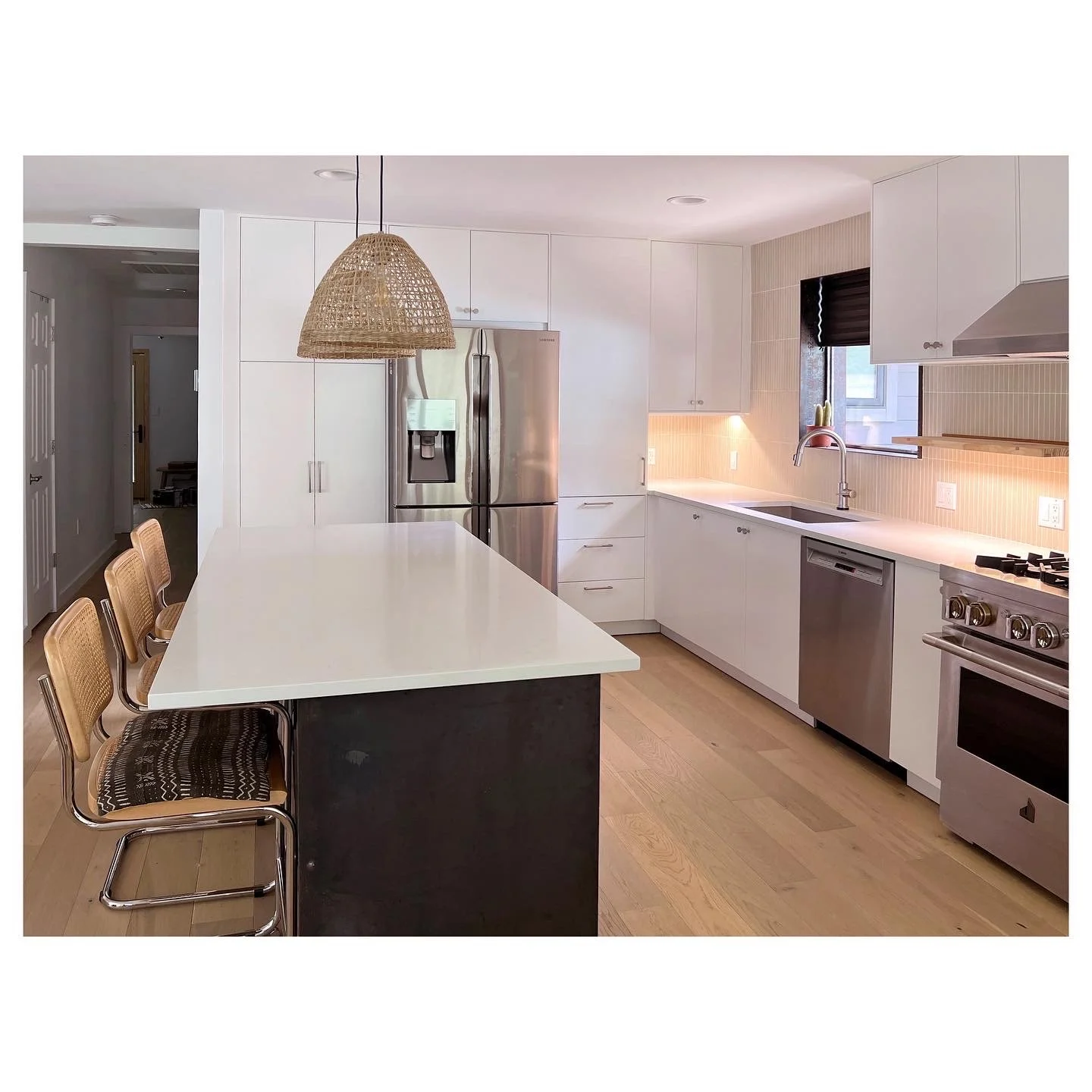 Modern kitchen with white cabinets, stainless steel appliances, and a large island with seating.