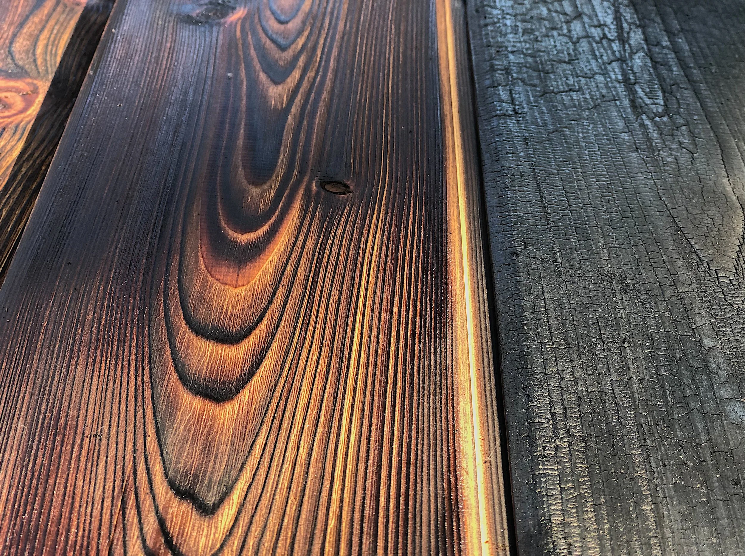Close-up of wooden planks with one side burned, showing different textures and colors.