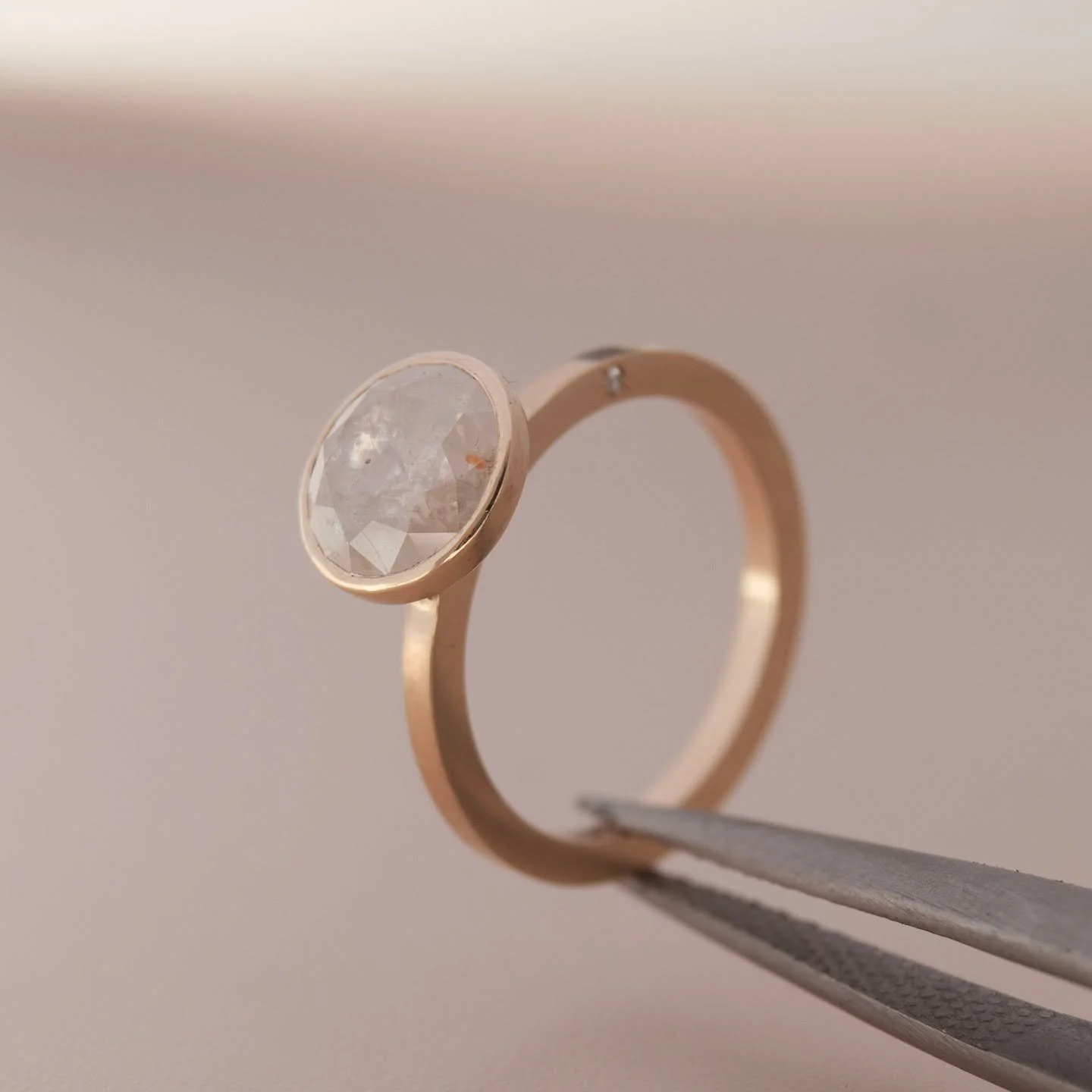 *SOLD*
This ring is where Modern and Rustic come together in perfect harmony. A deeply textured and opalescent Diamond with flecks of red, black, white, and gold sits atop an elegant and ultra-minimalist &lsquo;Saturn&rsquo; setting. Two tiny star-se