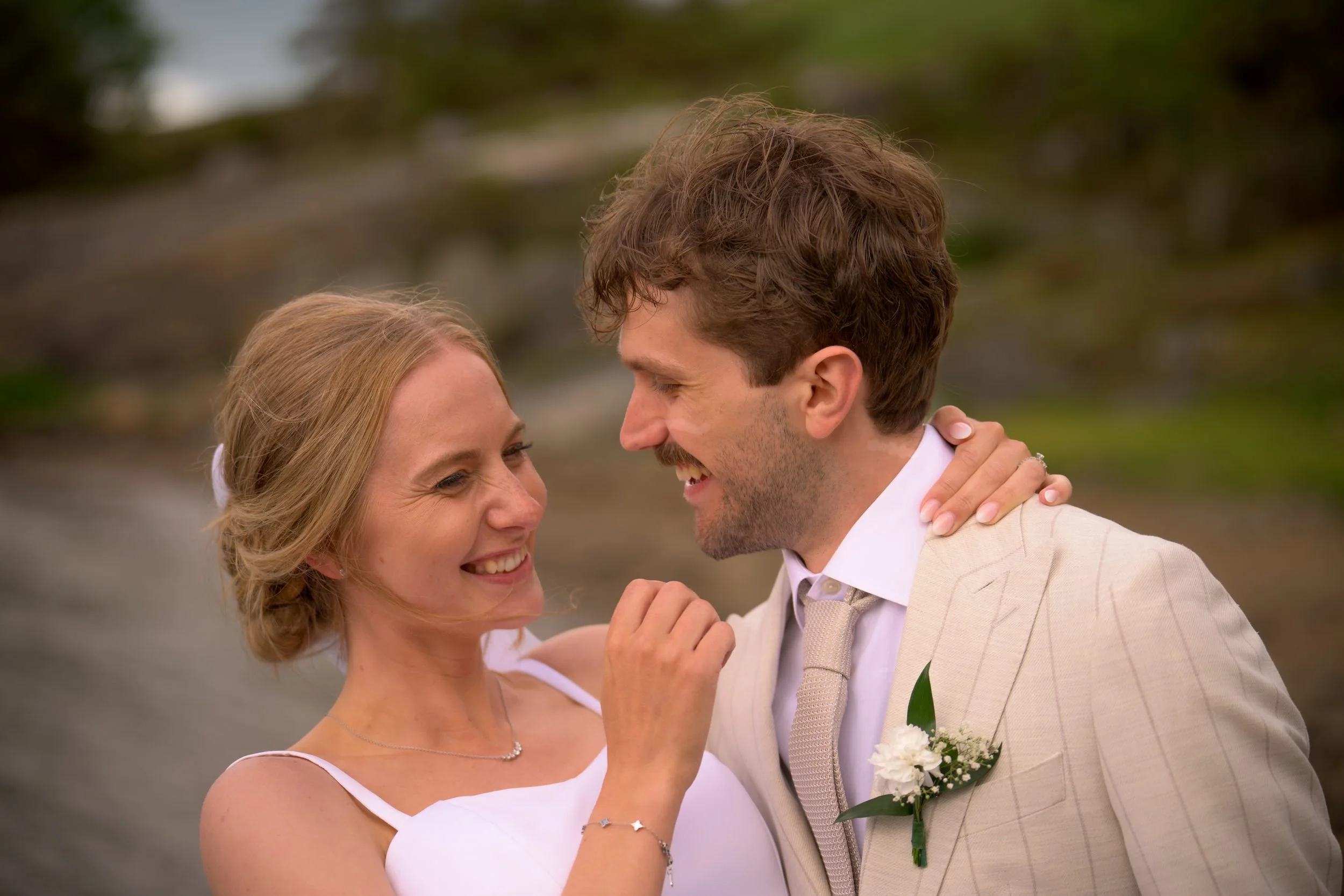 Bruden och brudgummen skrattar tillsammans i ett närporträtt vid vattnet – bröllopsfotografering på Villa Vanahem