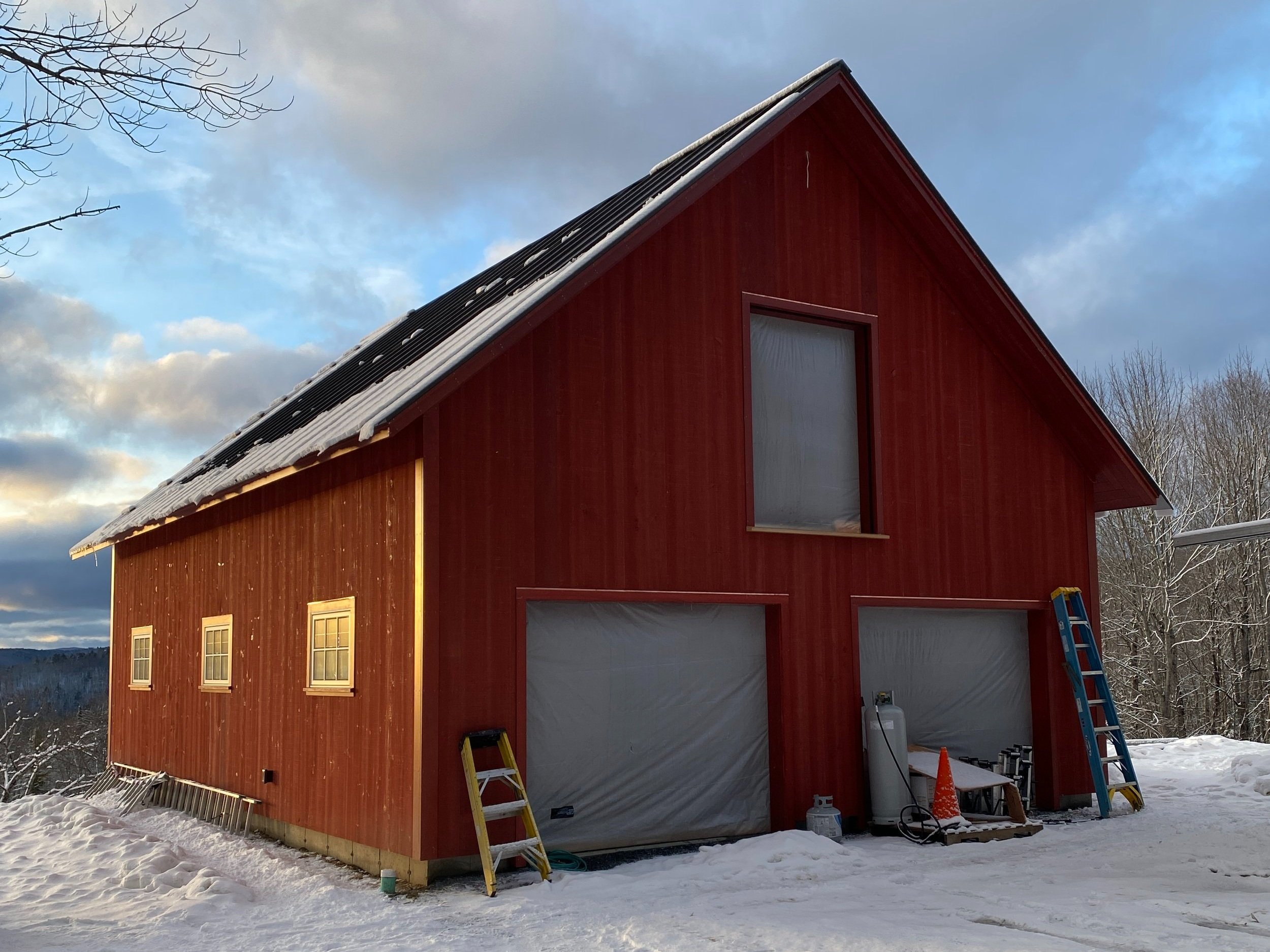 A nearly-finished red barn with two garage doors