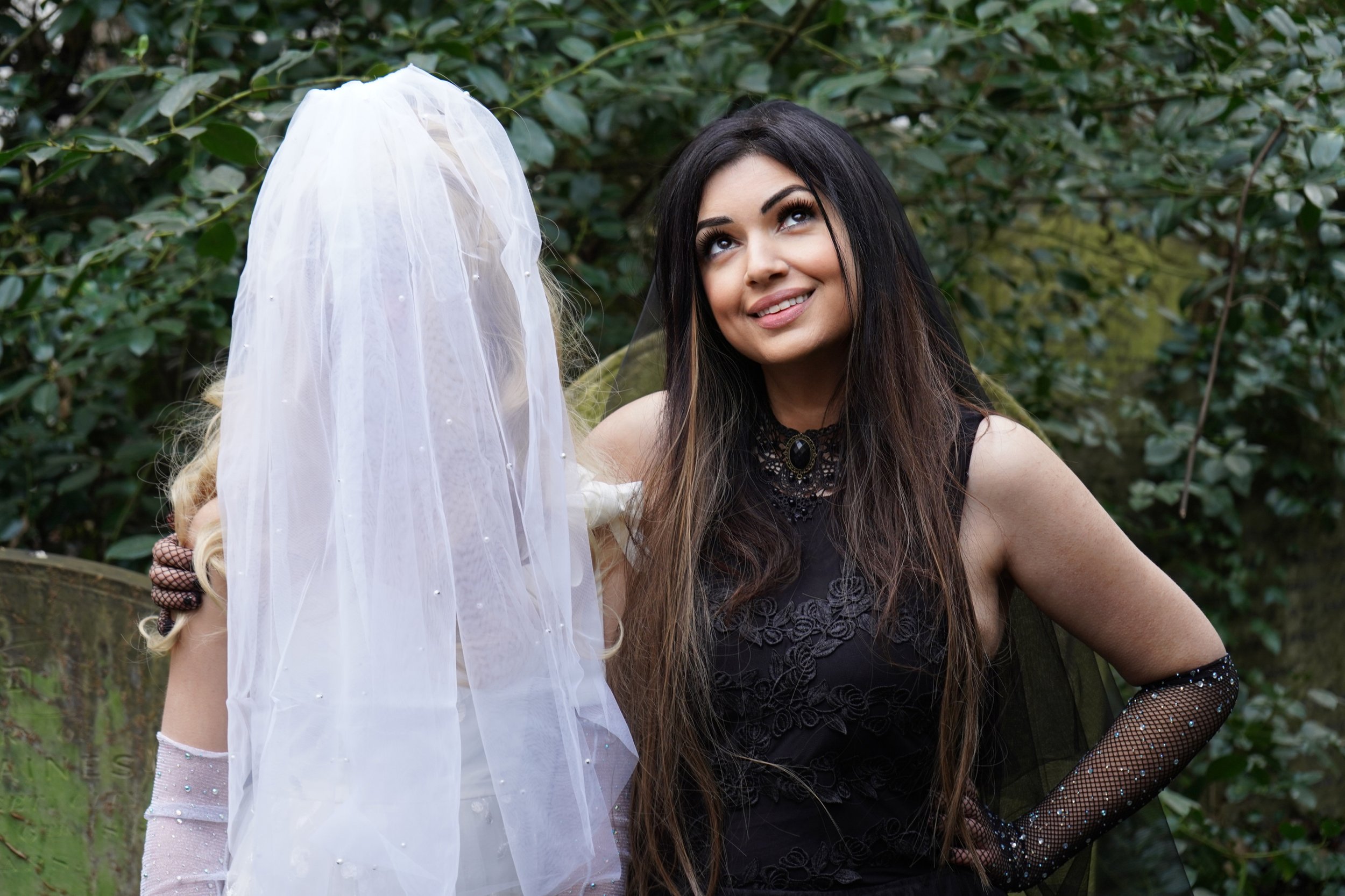 Ariane X dressed all in black in a graveyard with her daughter Lily dressed as an angel