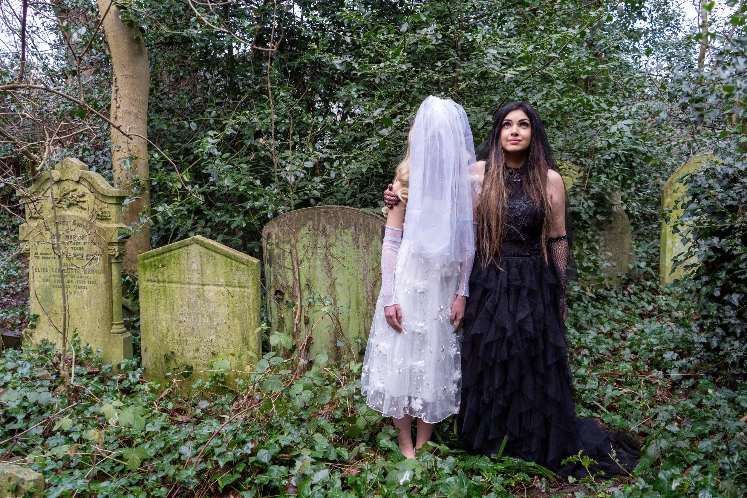 Ariane X dressed all in black in a graveyard with her daughter Lily dressed as an angel