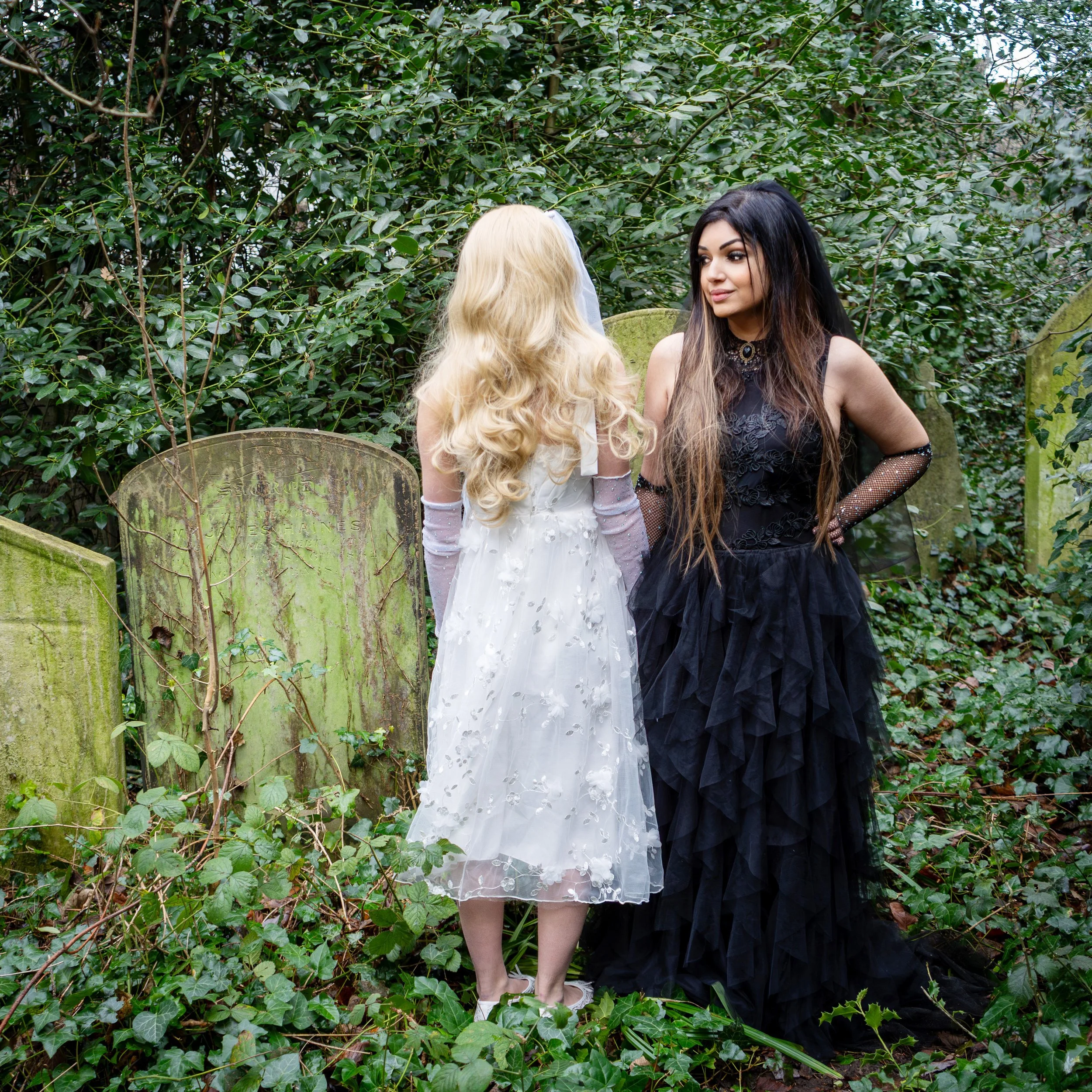 Ariane X dressed all in black in a graveyard with her daughter Lily dressed as an angel