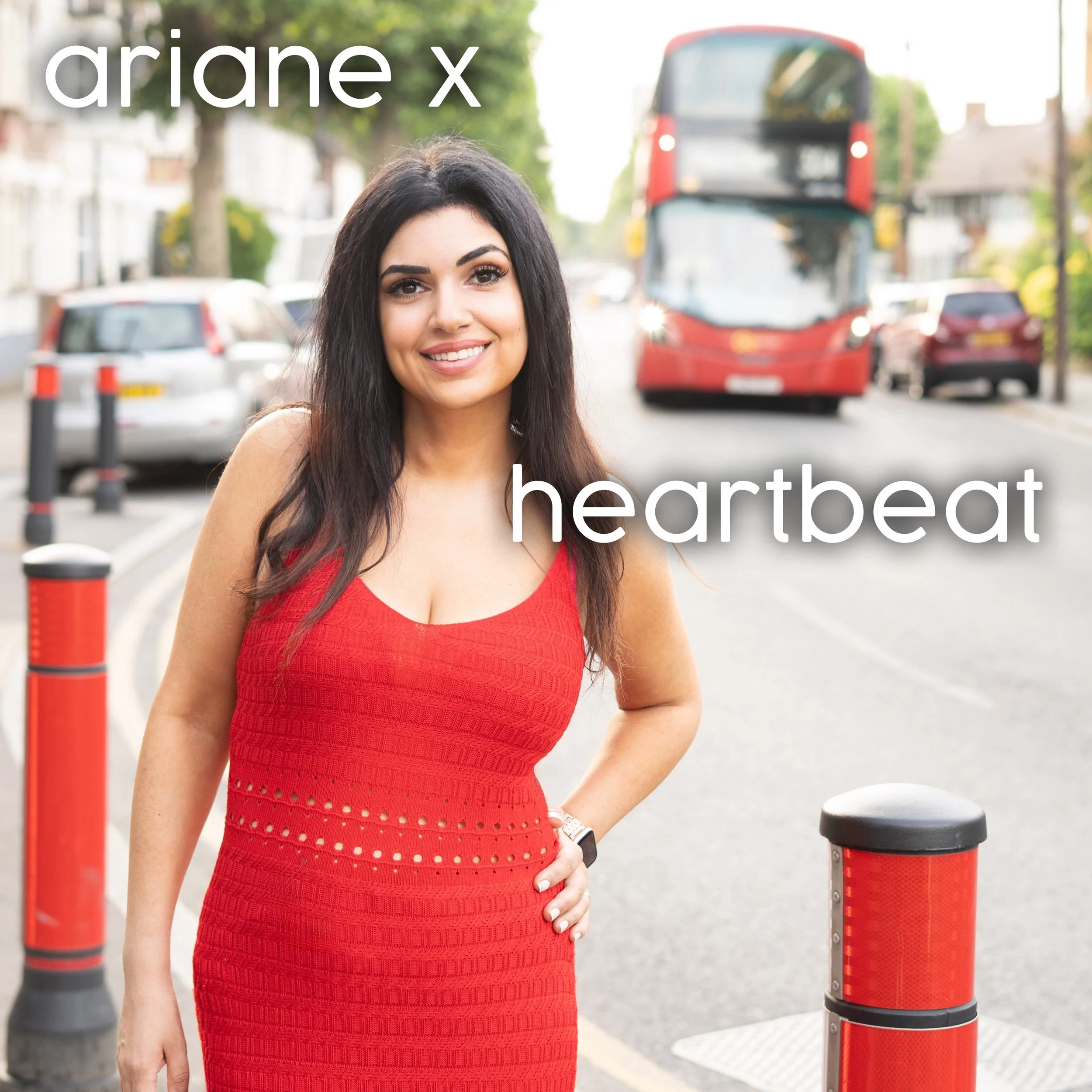 Ariane X dressed in red on a London street with a London bus behind her