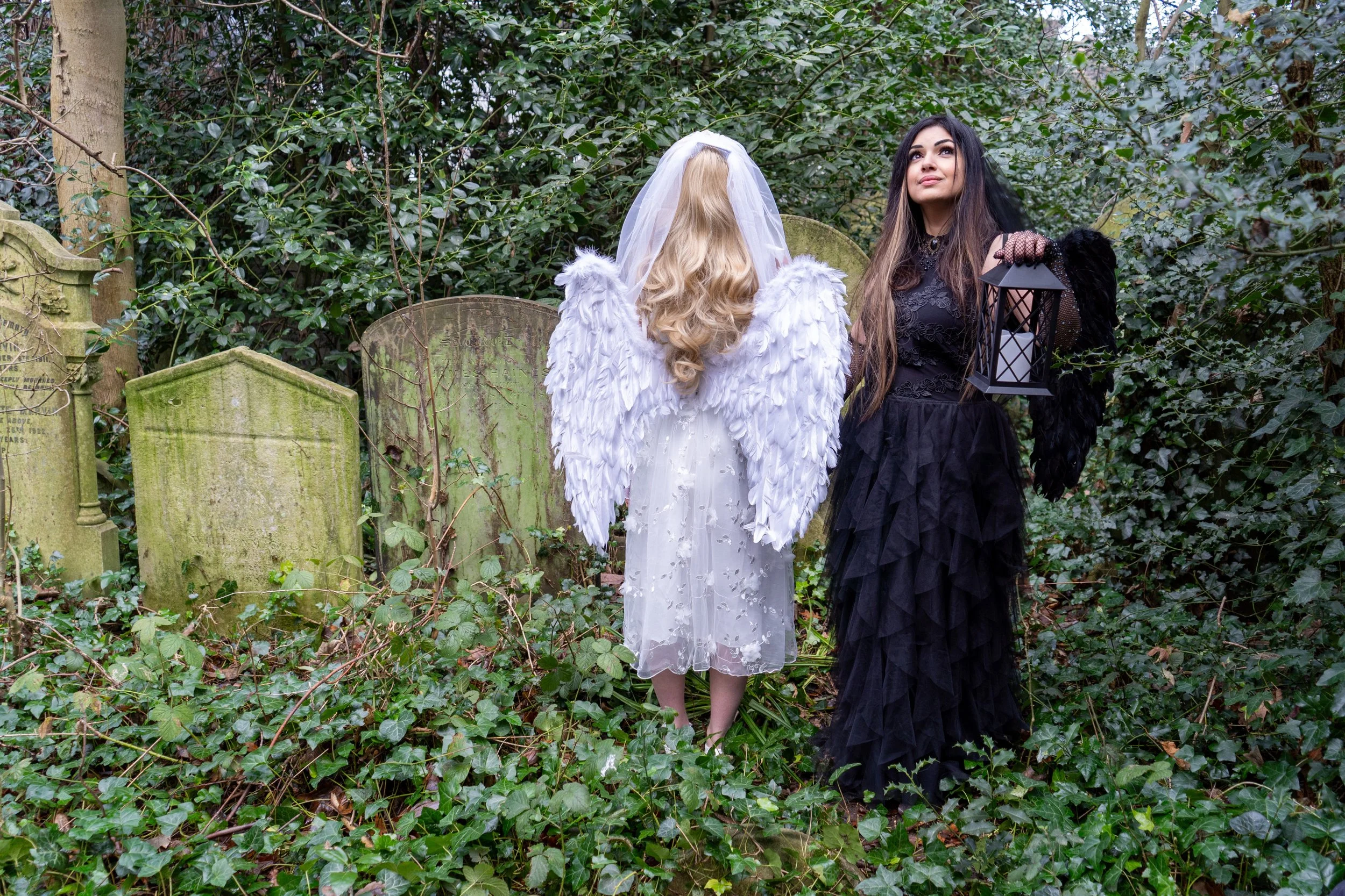 Ariane X dressed all in black in a graveyard with her daughter Lily dressed as an angel
