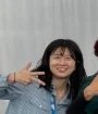 A person in a striped shirt smiling and making a peace sign with their hand.
