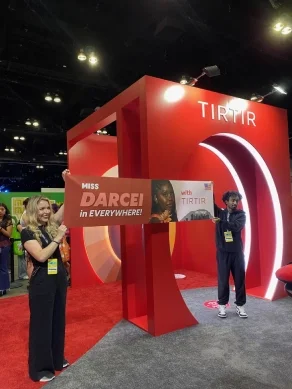 People holding a banner at the TIRTIR booth at an event, with red and white decor.