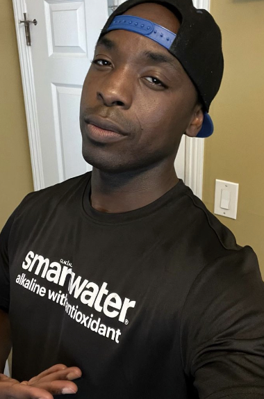 Person wearing a black Smartwater t-shirt and black cap.