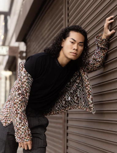 Person wearing patterned jacket posing against metal shutter