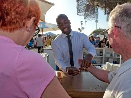 A bartender serving drinks outside at a sunny event.