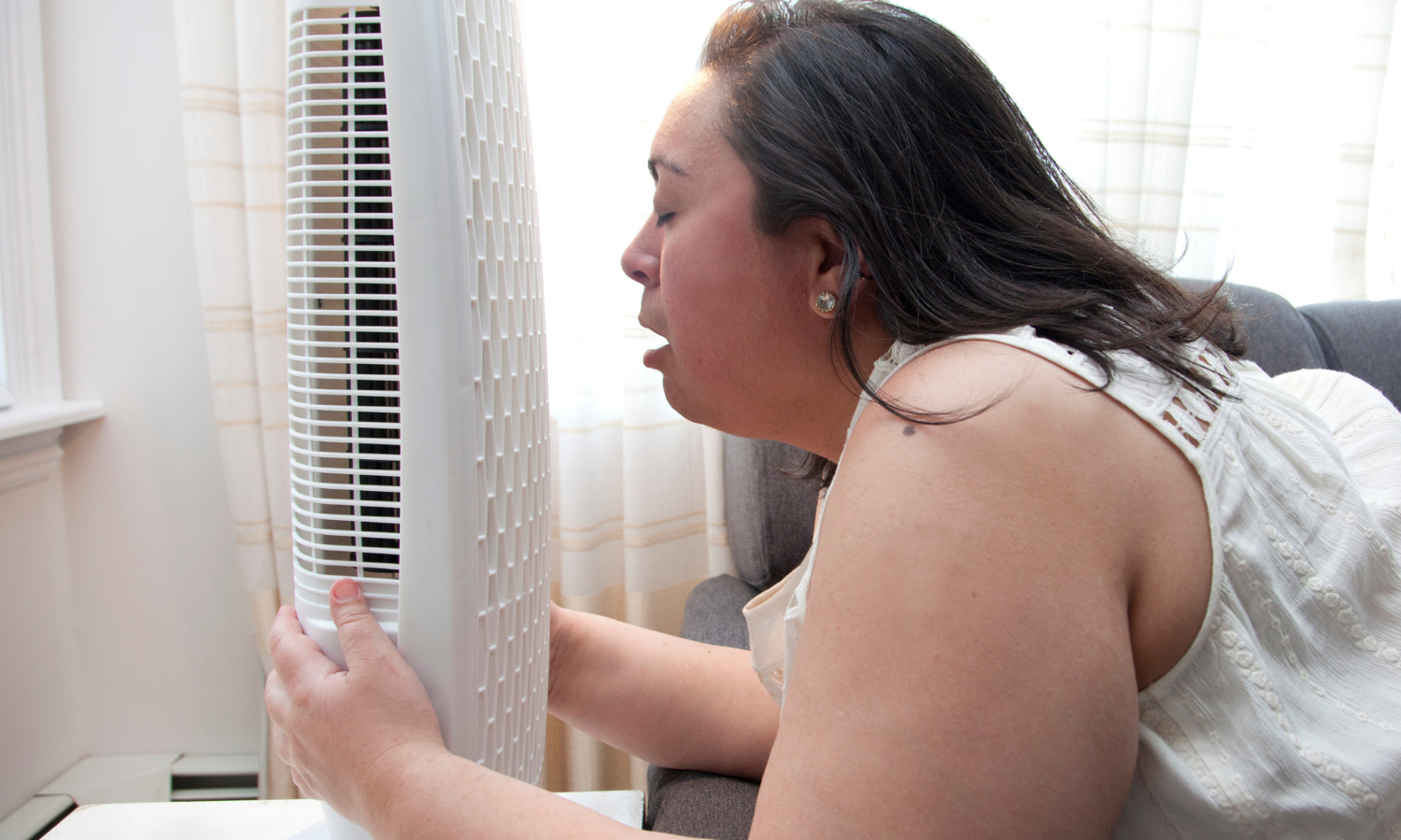 A woman cooling herself off in front of a fan