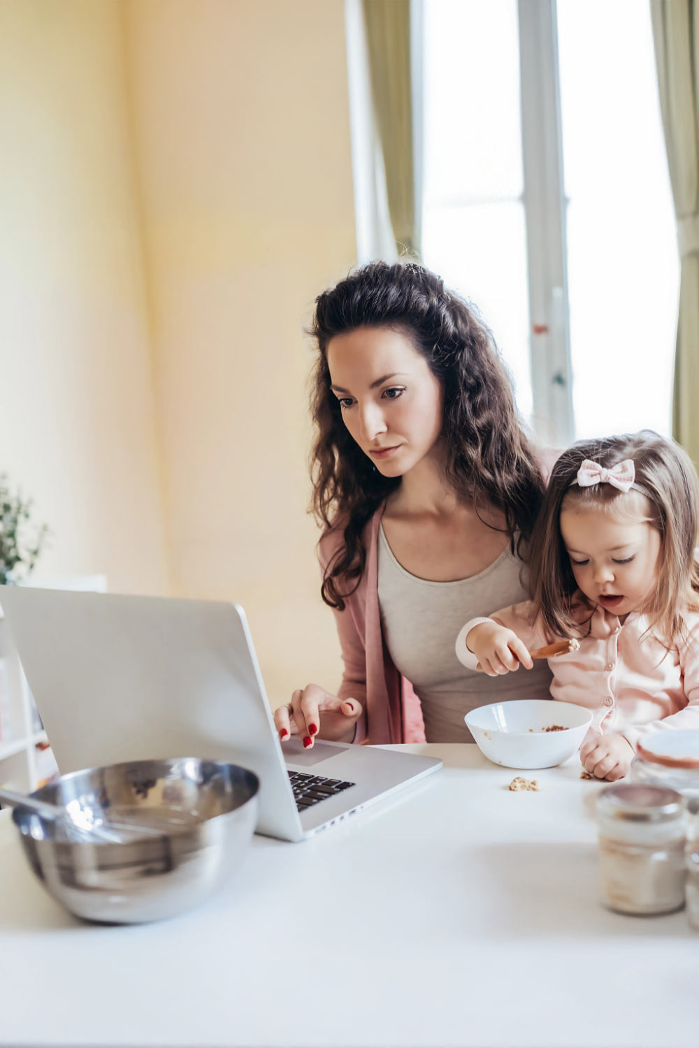 woman on laptop with child eating breakfast