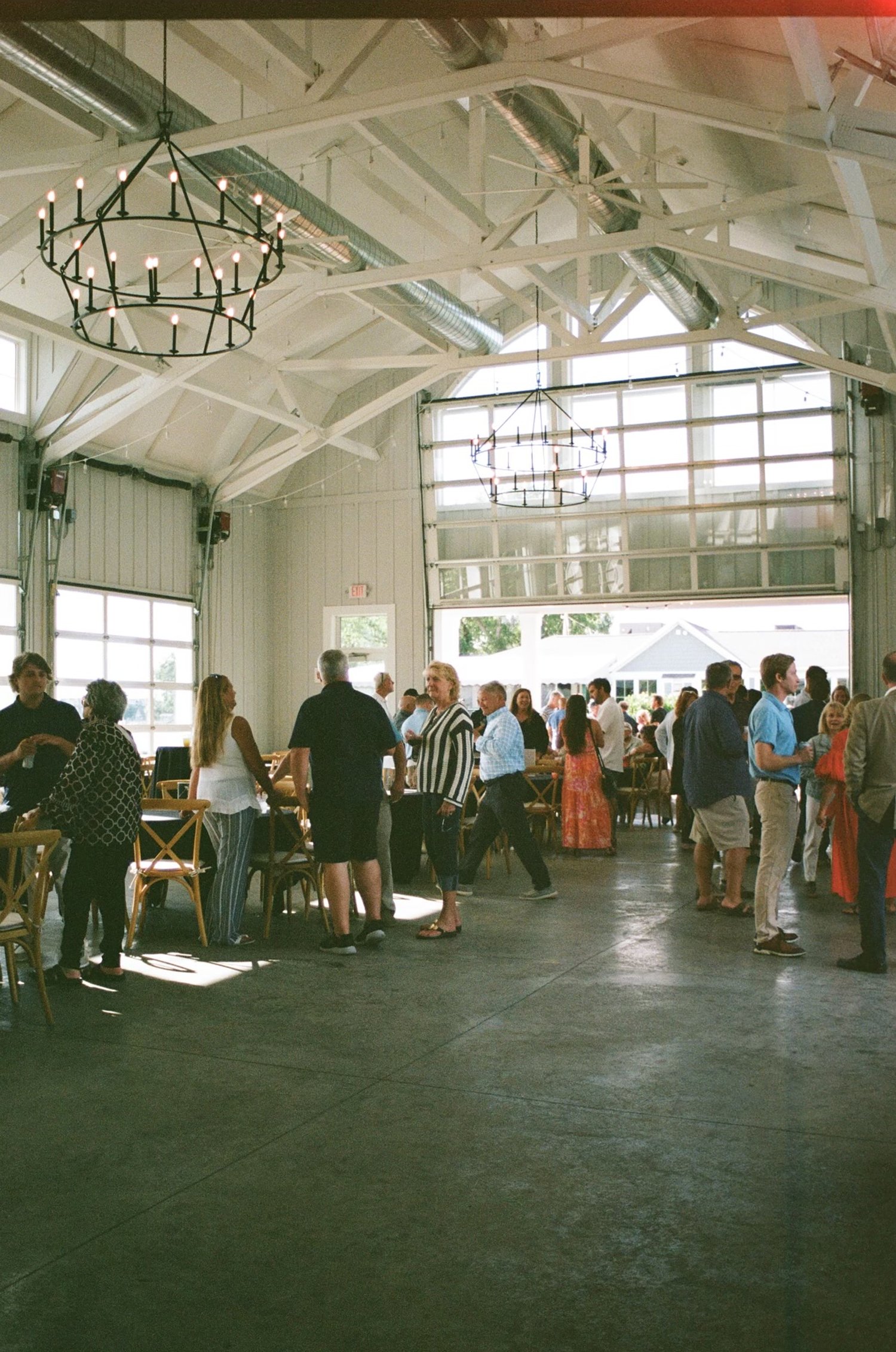 People socializing in a spacious indoor venue with high ceilings and large windows.