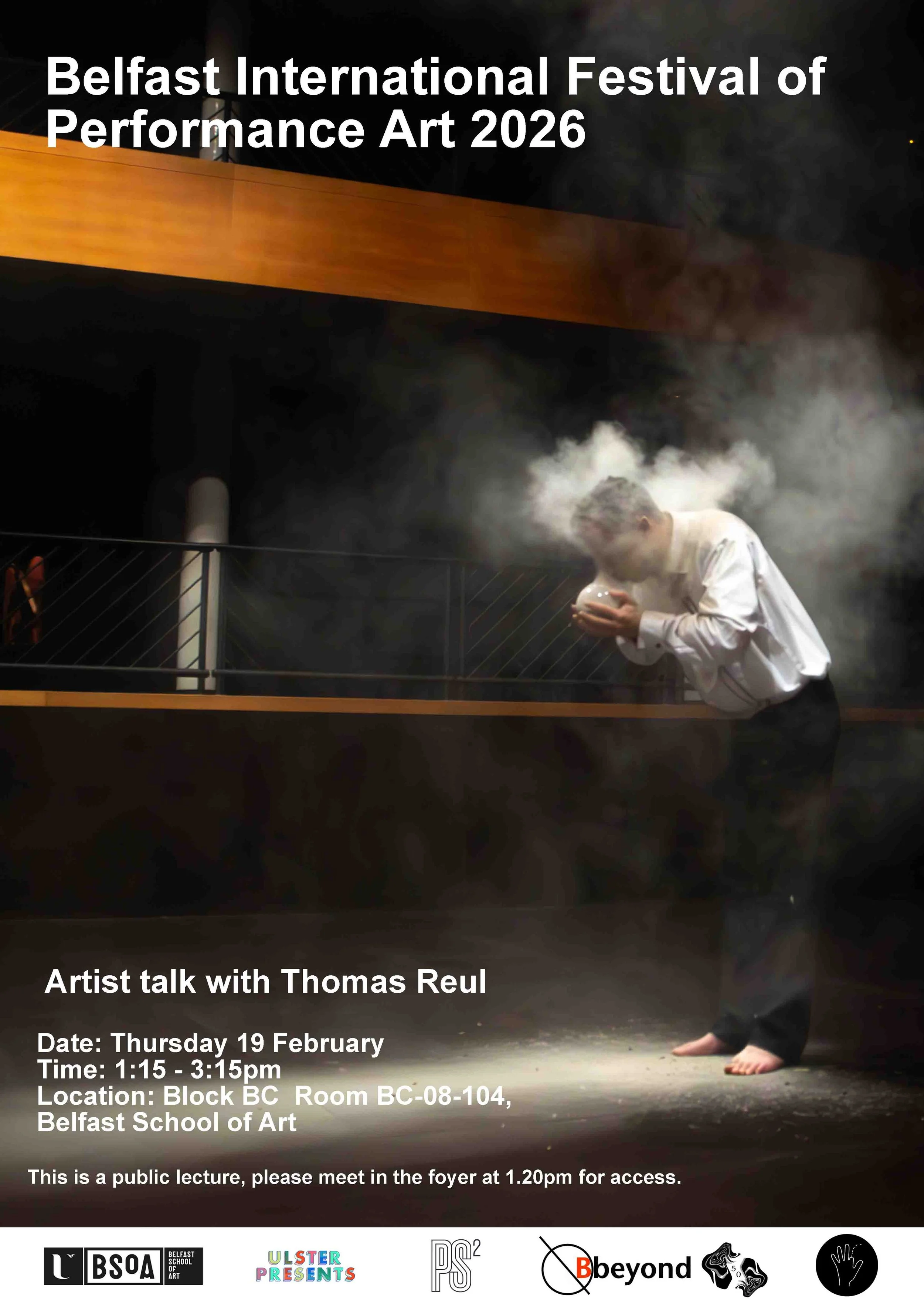 man in a white shirt and dark trousers blowing into a glass bubble with smoke billowing around his face, in a darkened space.