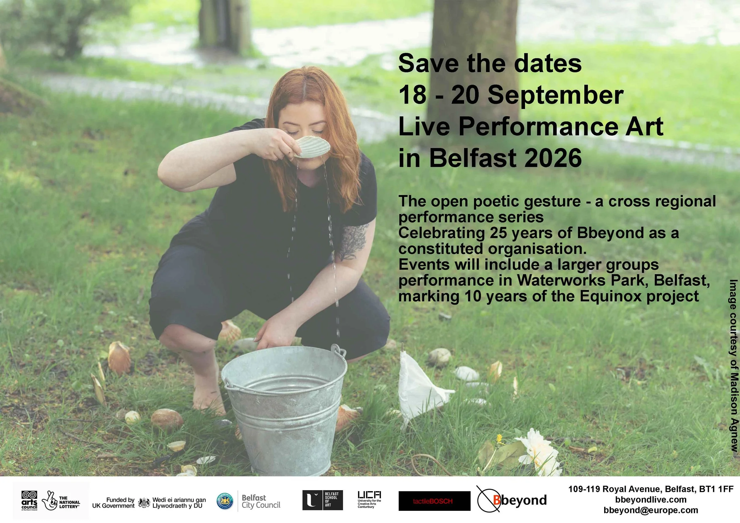 photo of a femail with long red hair, wearing black siting on grass drinking water from a scallop shell with a bucket in front of her