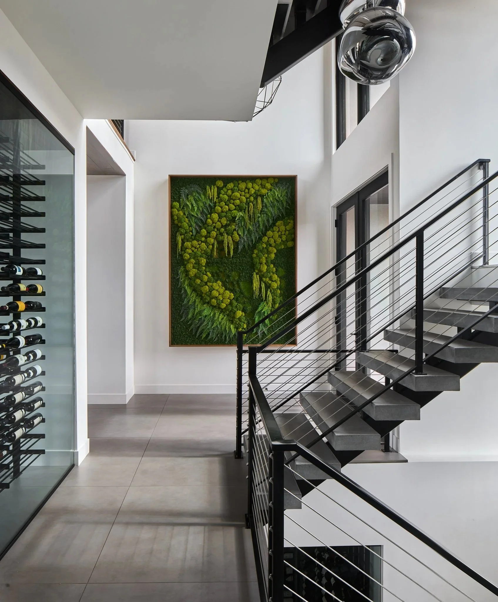 Modern interior staircase with black metal railing and a green wall art on white wall
