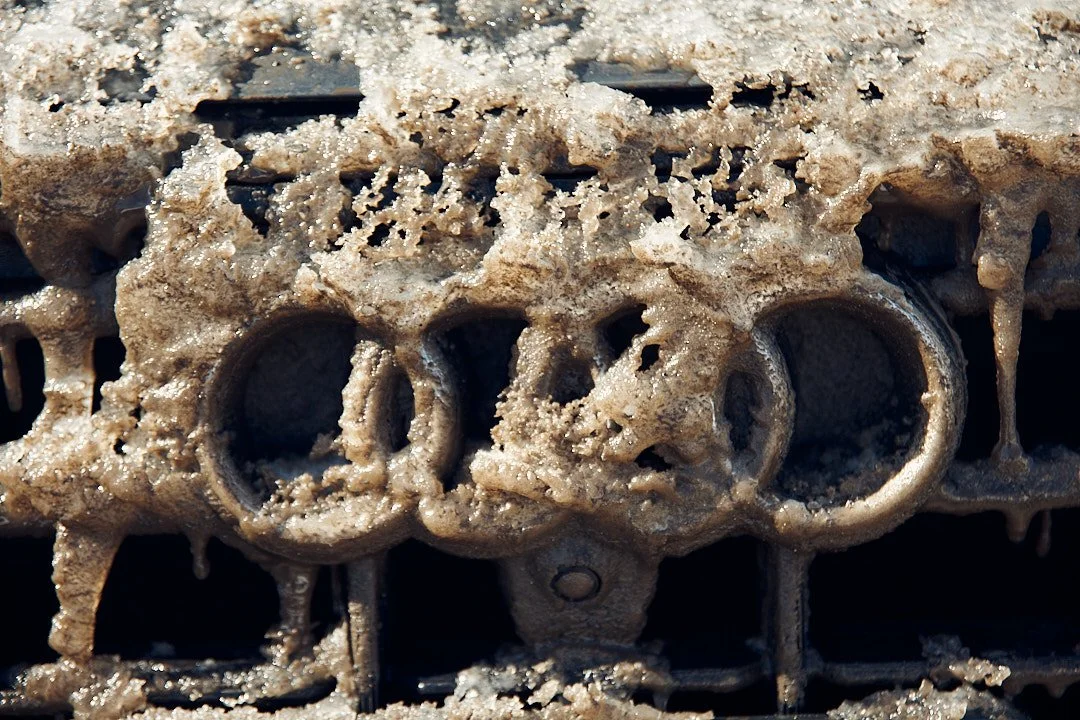 Close-up of a dirty, mud-covered motorcycle engine with visible cylinders and parts