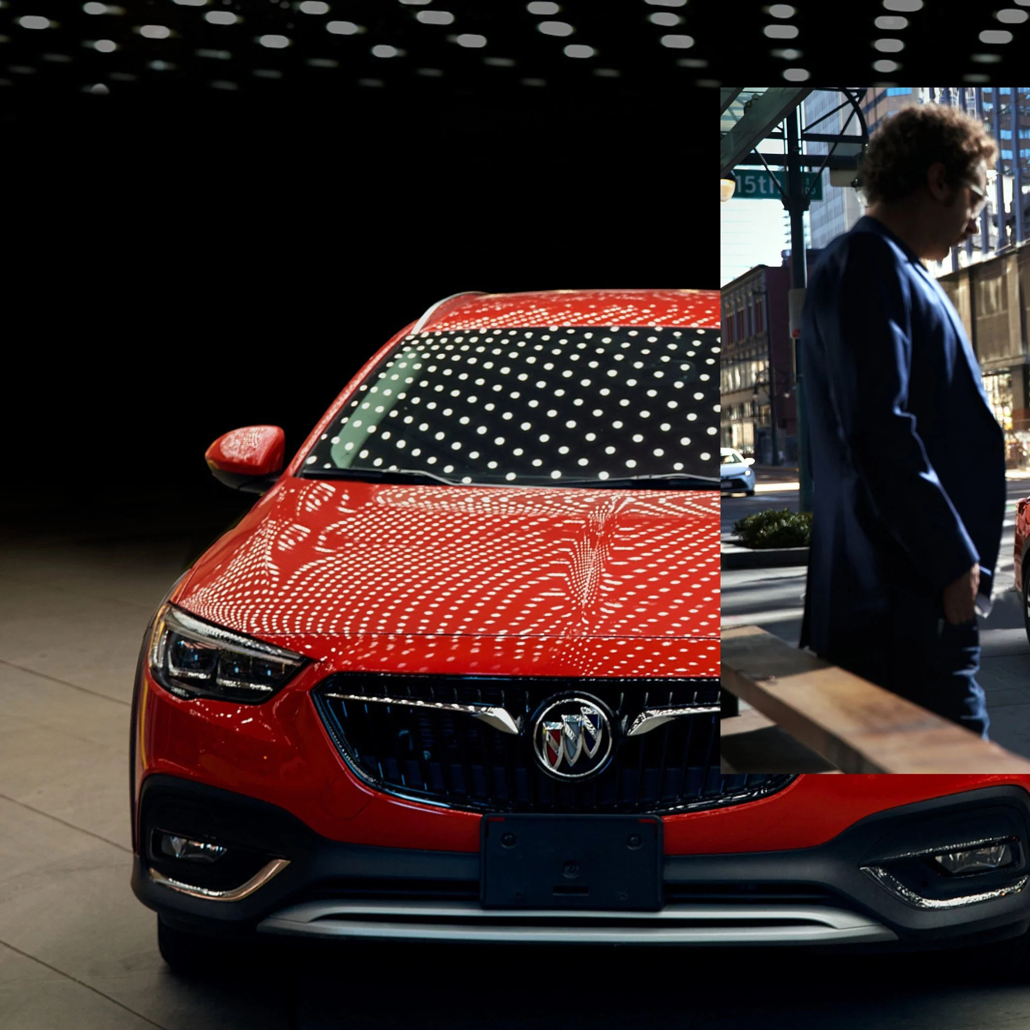 Red Buick sedan parked indoors with reflections of ceiling lights on its hood and windshield.