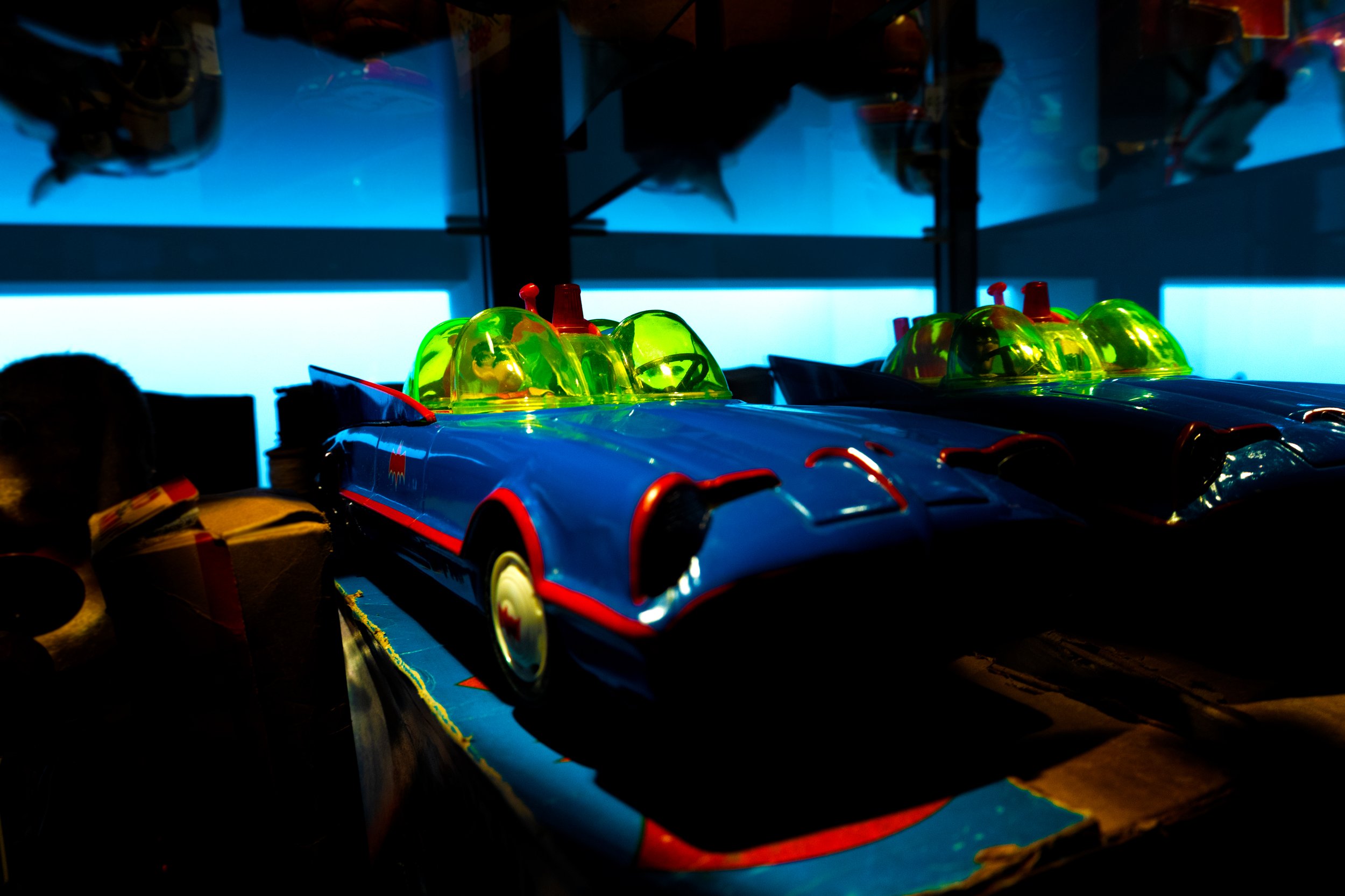 Kleurrijke speelgoedauto's met groene daken en blauwe lichamen op een donkere achtergrond.