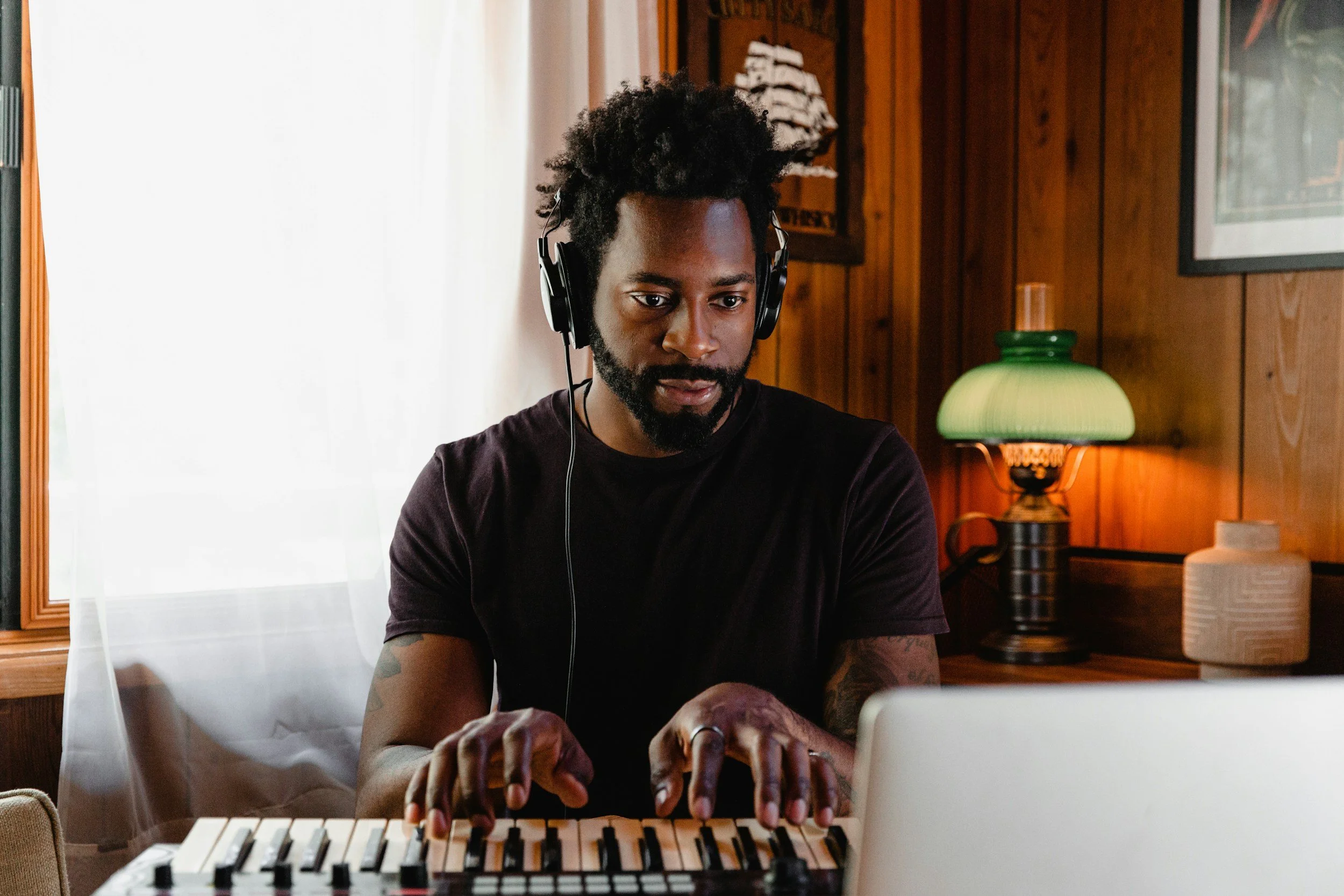 Person with headphones playing a keyboard at a wooden interior space.