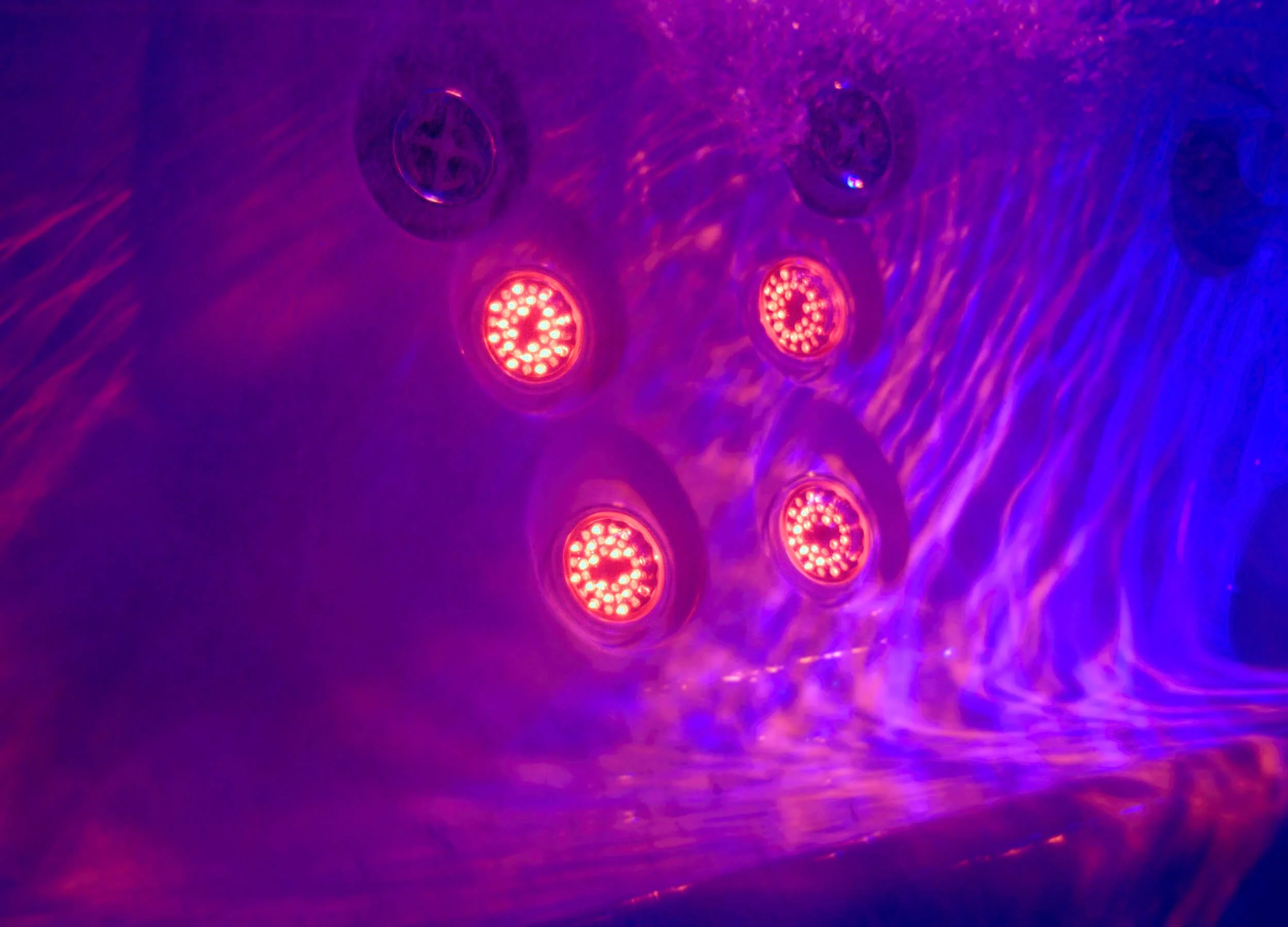 Close up view of Infrared + Red Light Therapy lights in a Jacuzzi® Hot Tub with purple/pink lighting in the tub's interior.