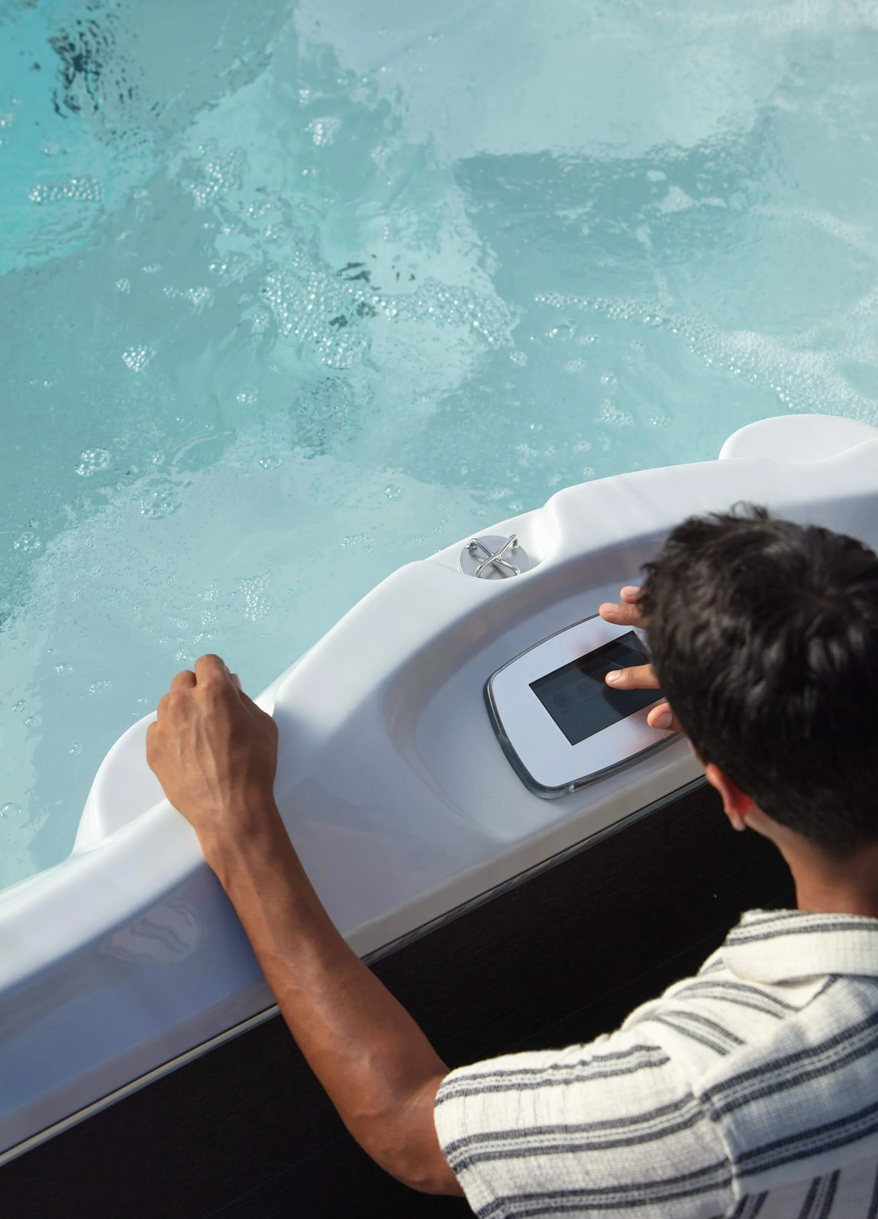 Overhead view of man adjusting controls on a Jacuzzi® swim spa.