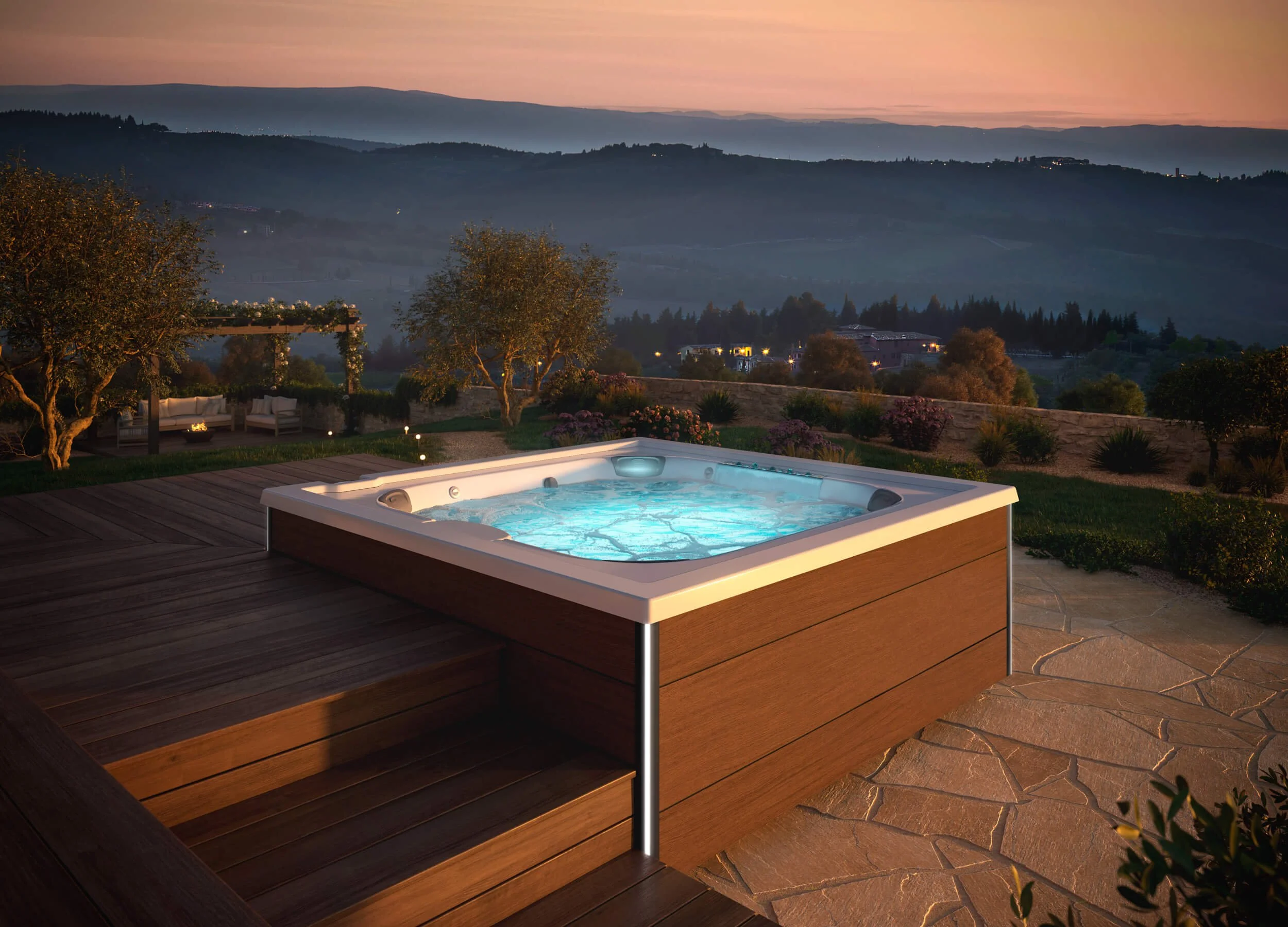 J408™ hot tub on flagstone patio with wood deck overlooking valley view at dusk.
